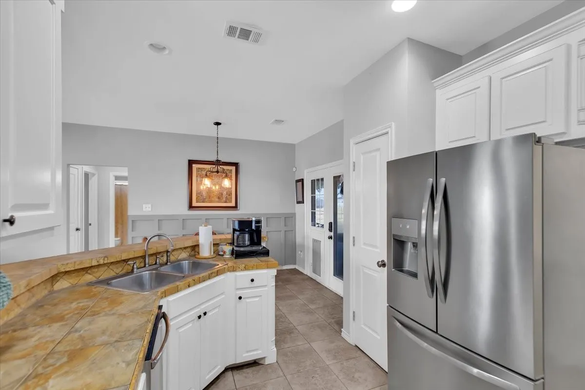 Kitchen featuring white cabinetry, a dual basin stainless steel sink, and a tiled countertop
