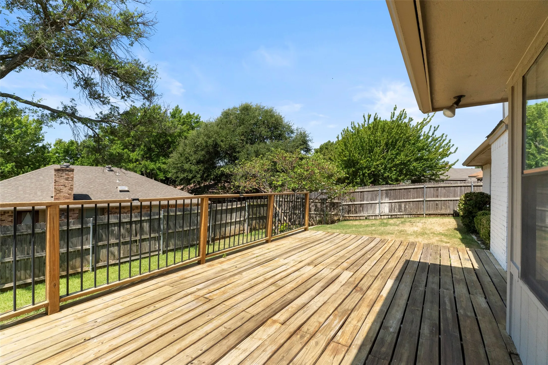 Expansive wood deck with black wrought iron and wood railing