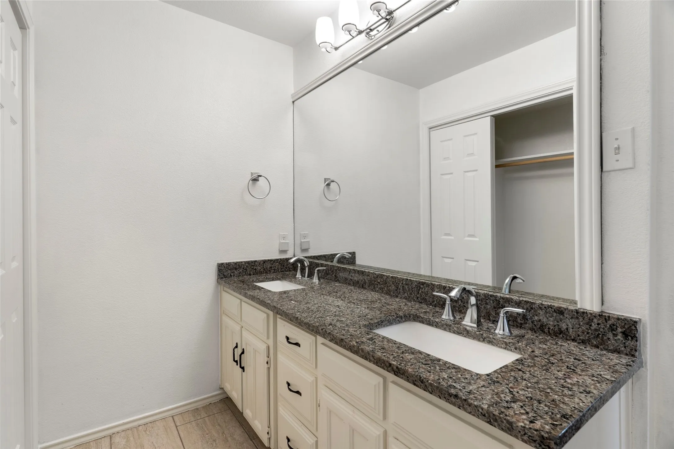 Dual vanity with granite countertop, integrated rectangular sinks, and chrome fixtures