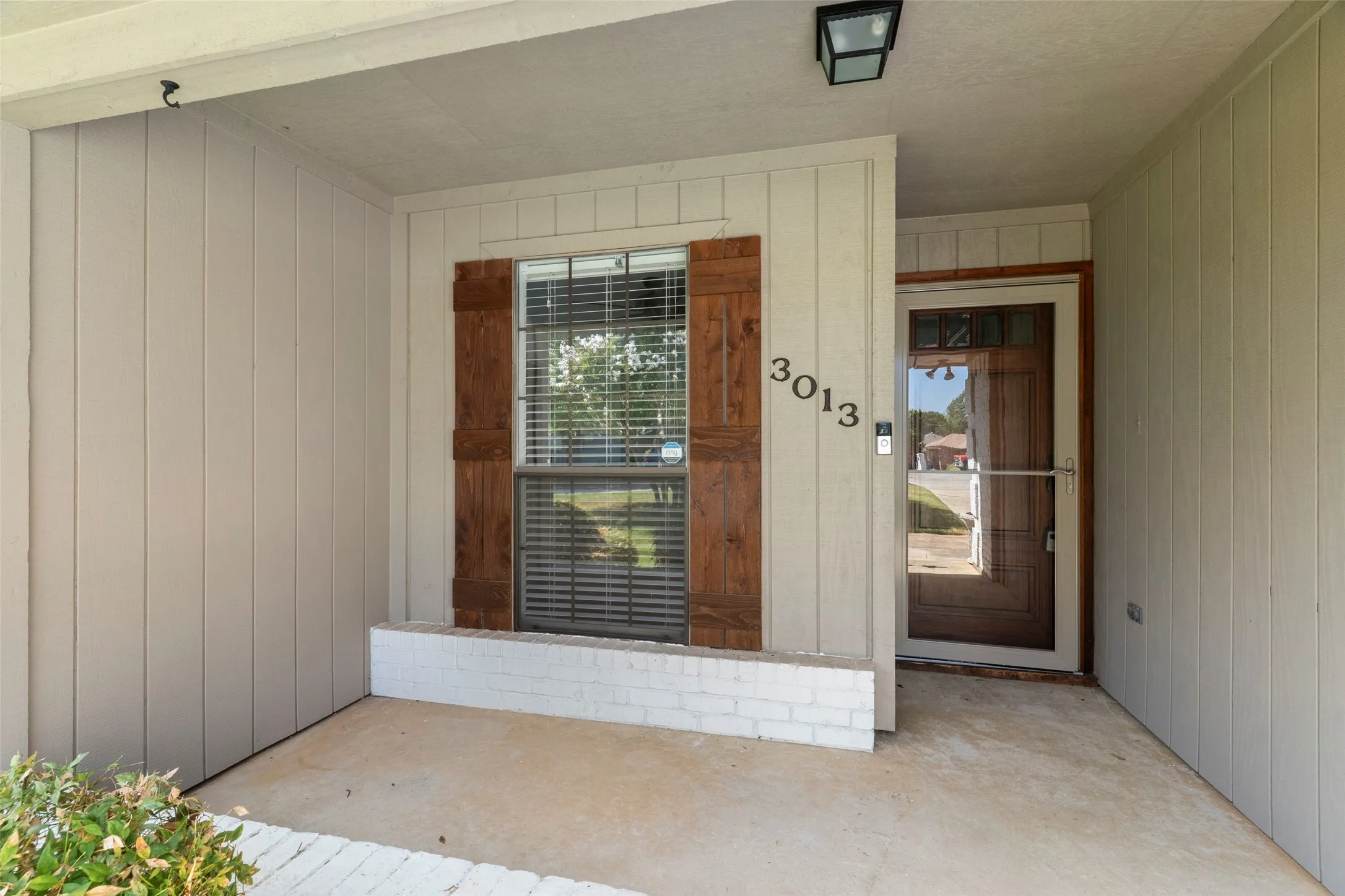 Covered entry featuring wood-finish siding, a window with wood shutters, and a glass-paneled entry door