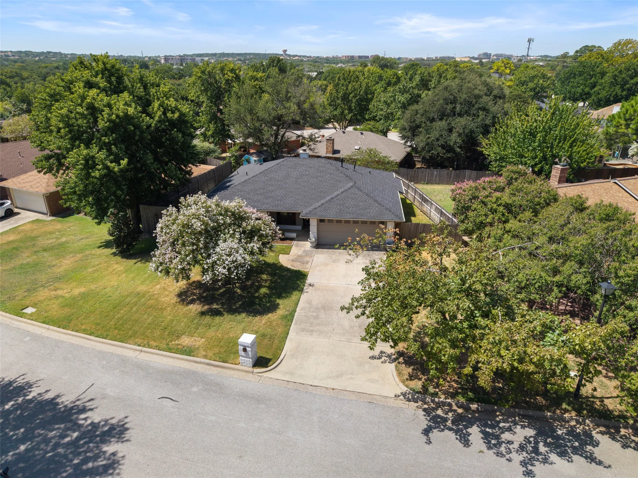 Single-story residence featuring a dark shingle roof, attached garage, concrete driveway, and front lawn