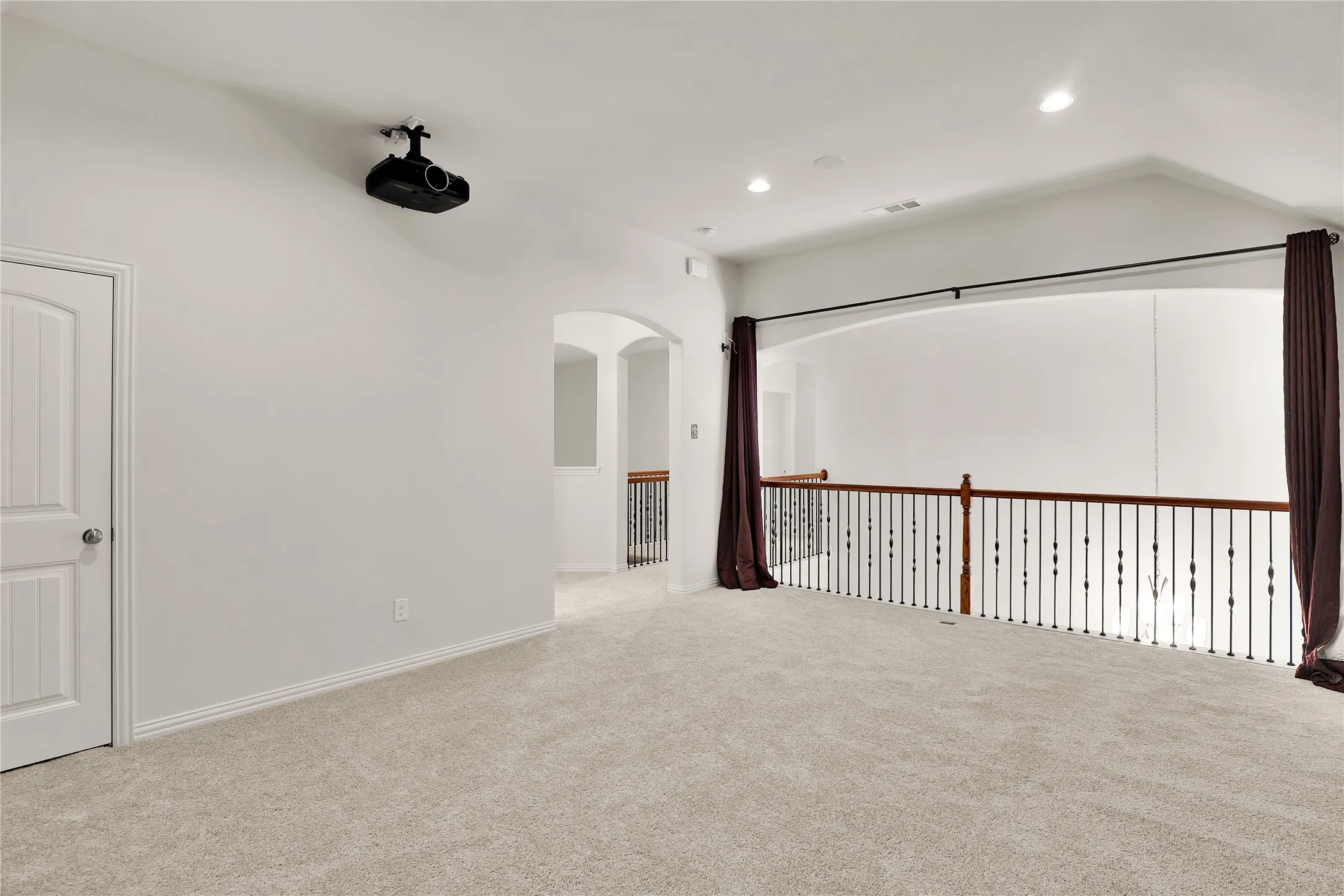 Carpeted space with a mounted projector, recessed lighting, and a white paneled door