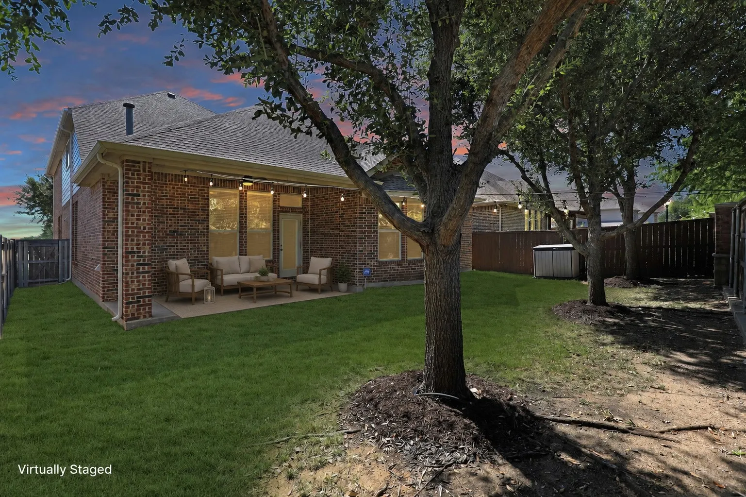 Expansive backyard featuring a manicured lawn, mature trees, and a brick exterior
