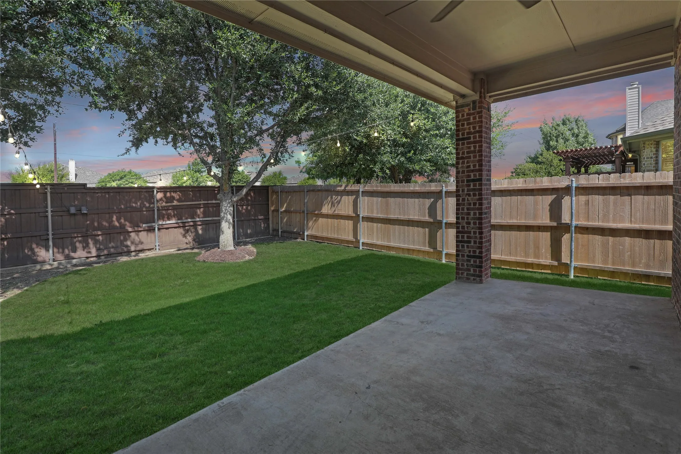 Covered patio with brick columns, concrete flooring, and a ceiling fan