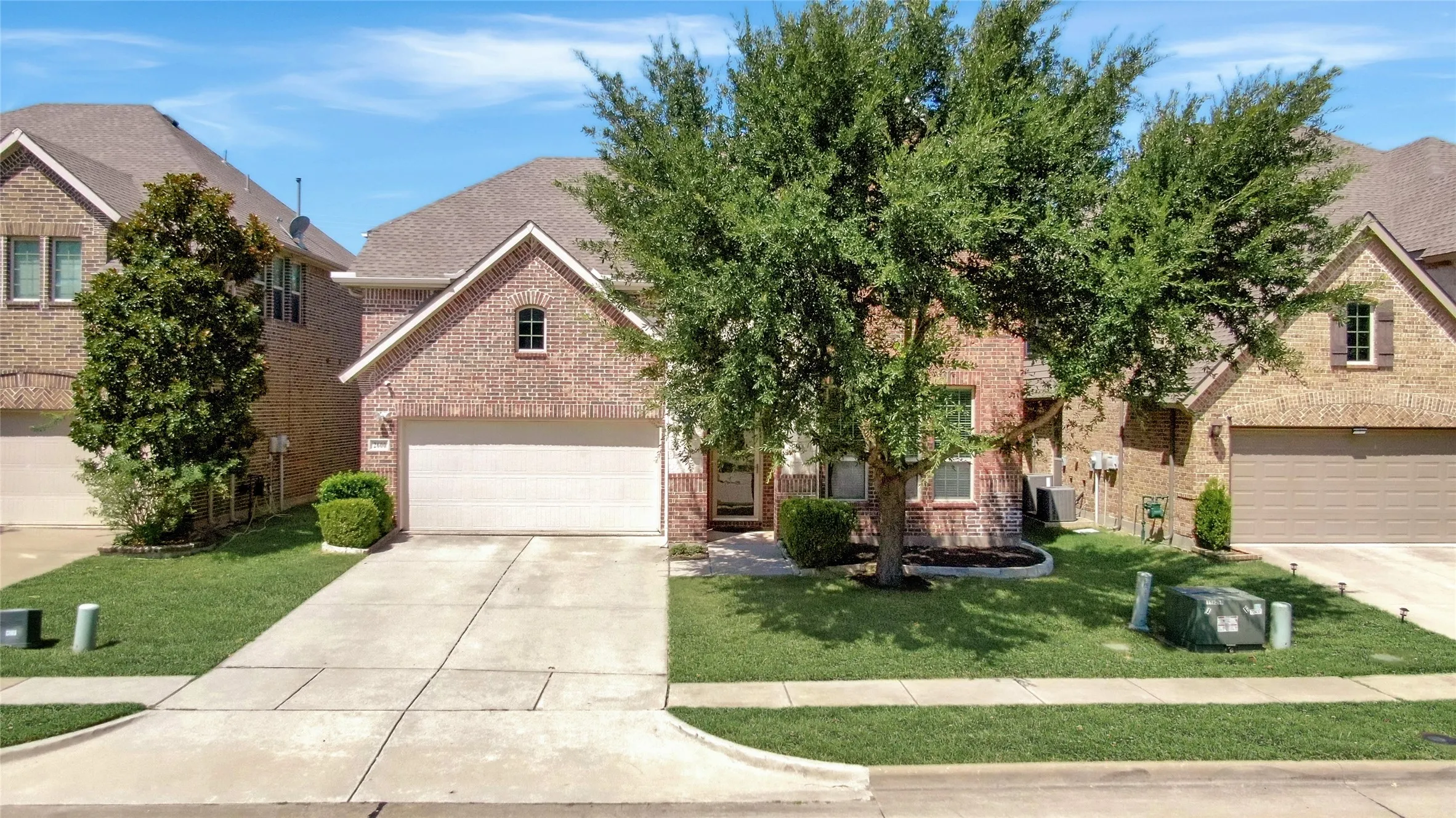 Brick facade residence with an attached two-car garage, concrete driveway, and front lawn