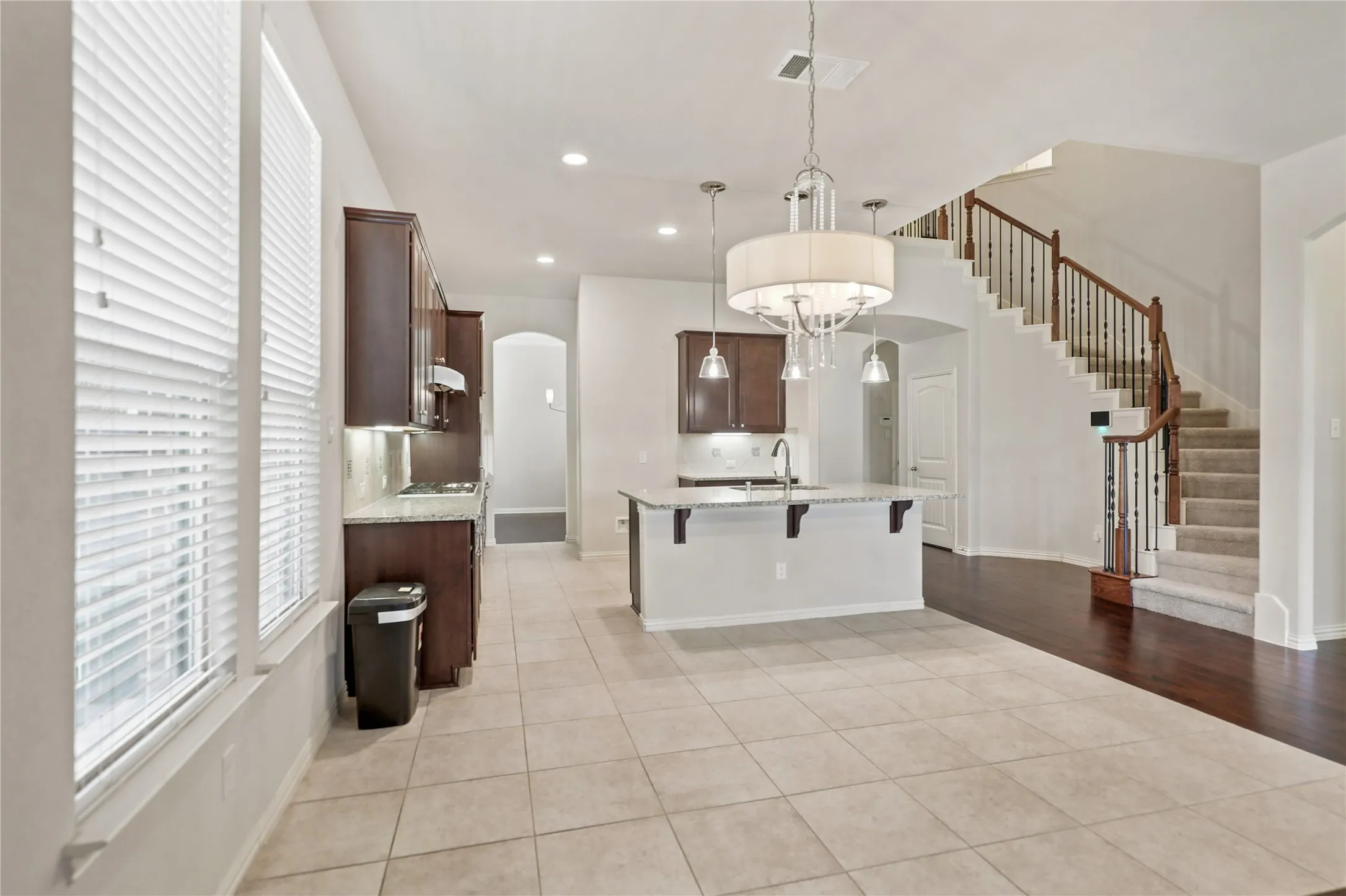 Kitchen featuring dark wood cabinetry, light-toned countertops, and a central island with pendant lighting