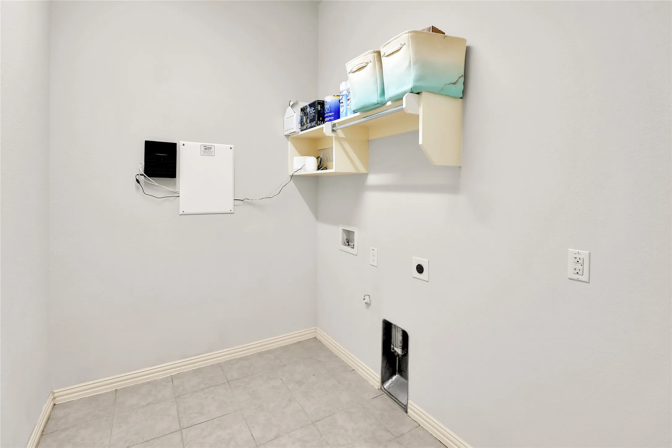 Utility space featuring a tiled floor, light-toned walls, and wall-mounted shelving