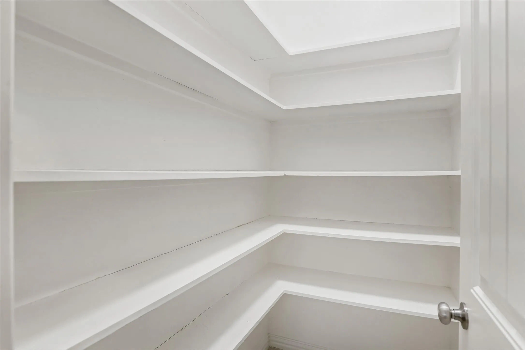 Built-in shelving with multiple levels, white finishes, and recessed ceiling lighting
