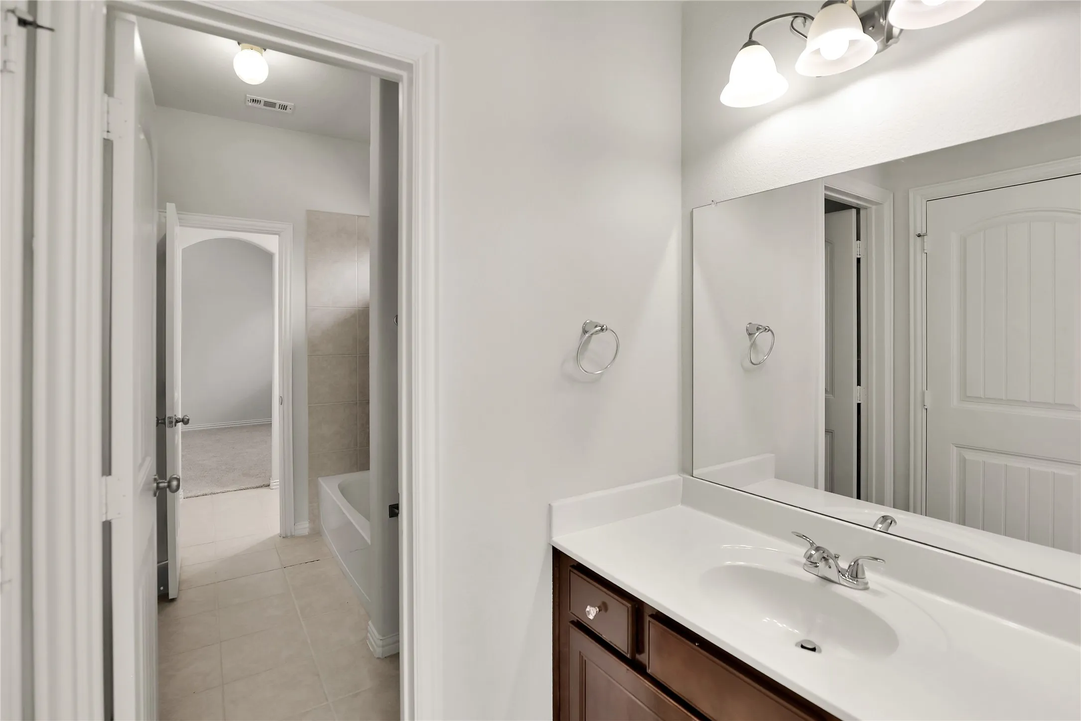 Bathroom vanity with a single basin sink, chrome faucet, and expansive wall mirror