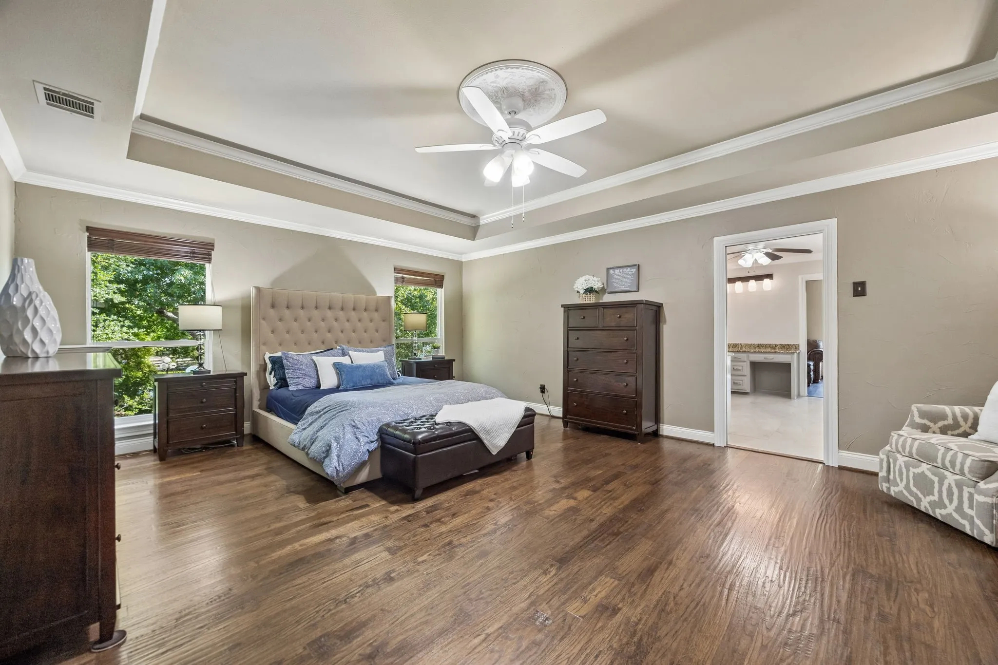 Spacious primary bedroom featuring wood-finish flooring and tray ceiling