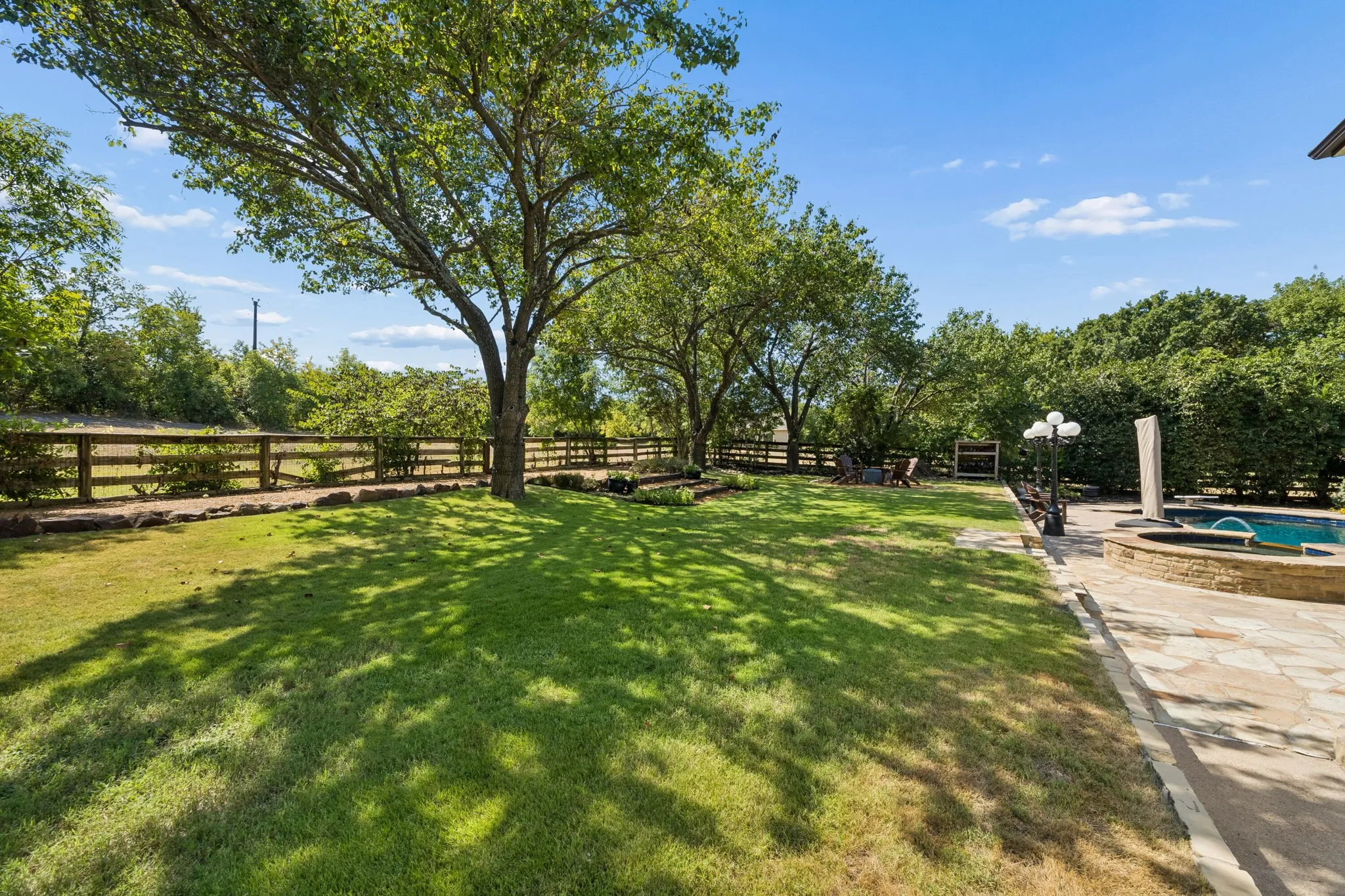 Expansive lawn area with mature trees and a wood fence