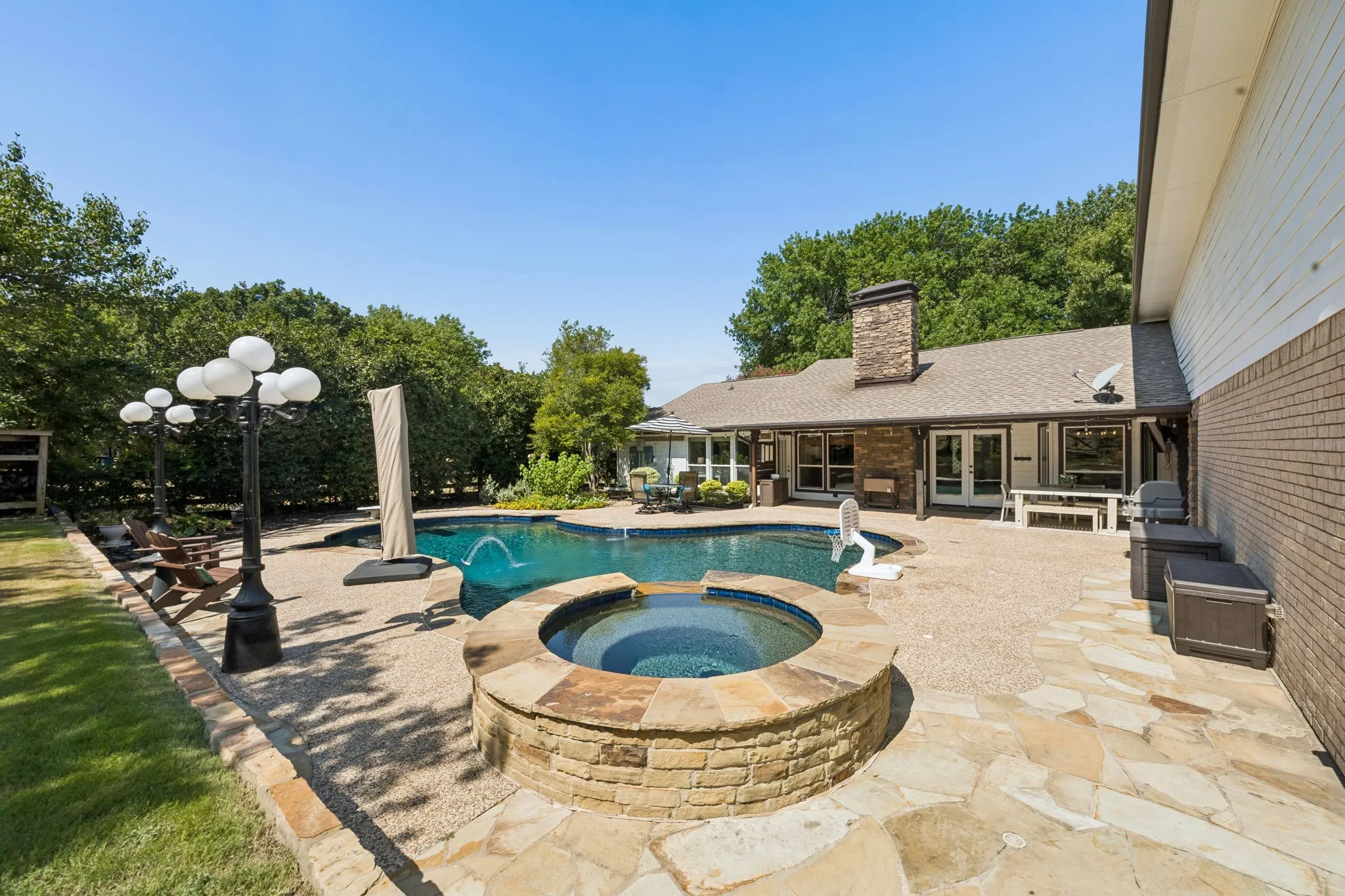 Outdoor swimming pool with built-in spa, expansive flagstone patio