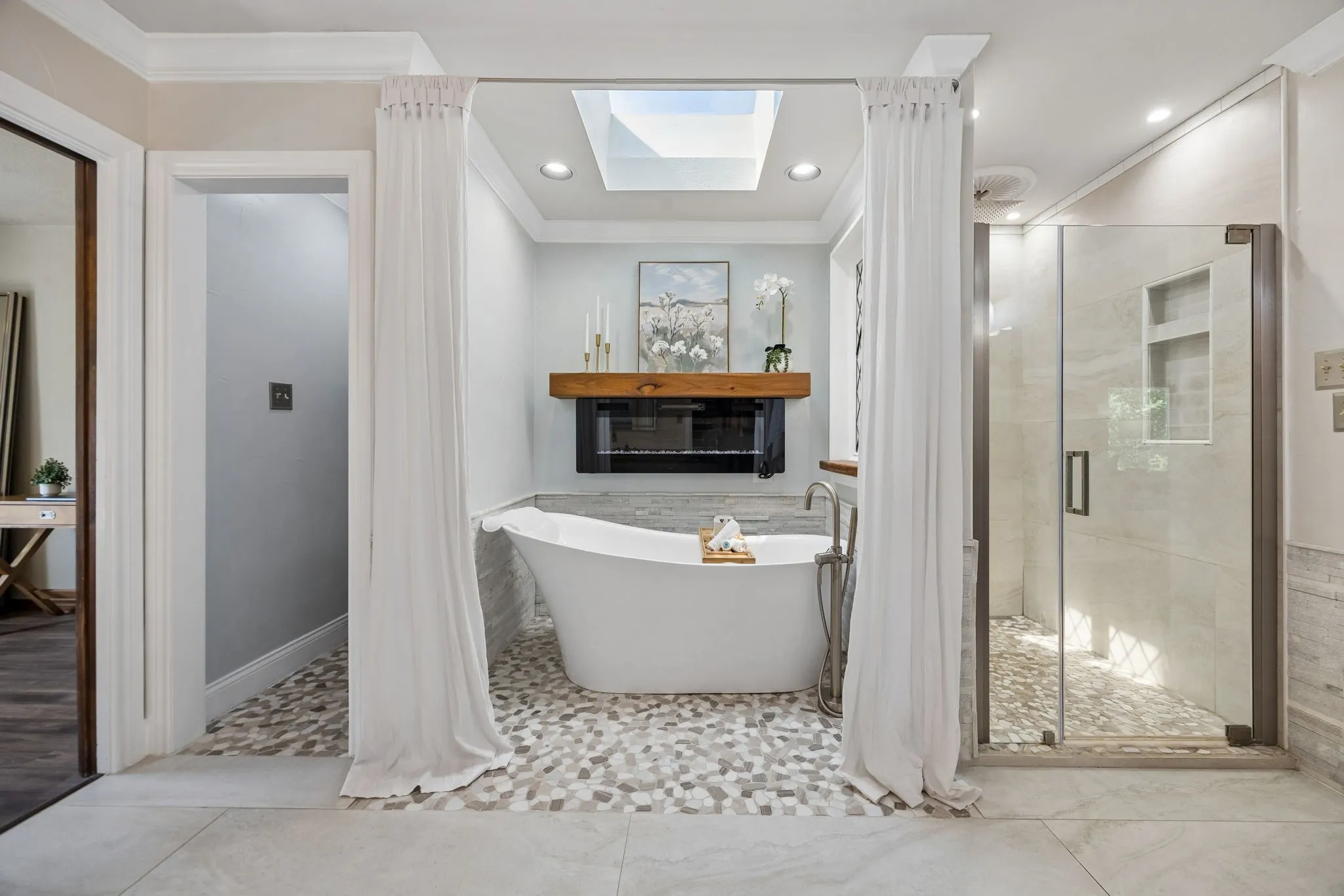 Freestanding soaking tub, glass-enclosed shower, mosaic tile flooring, skylight, and fireplace make for the ultimate relaxation space