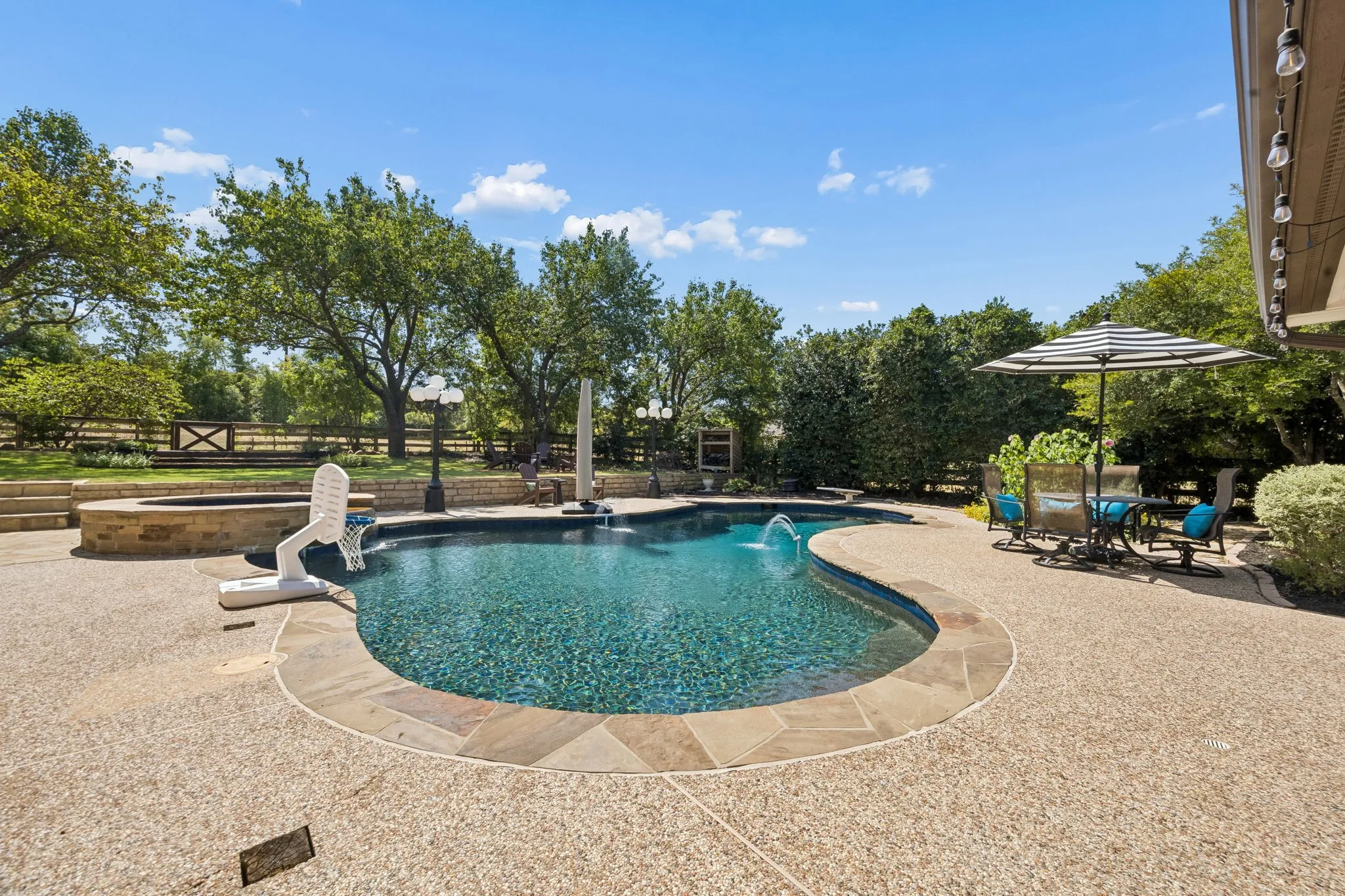 Expansive outdoor area featuring swimming pool with a built-in spa, and a flagstone border