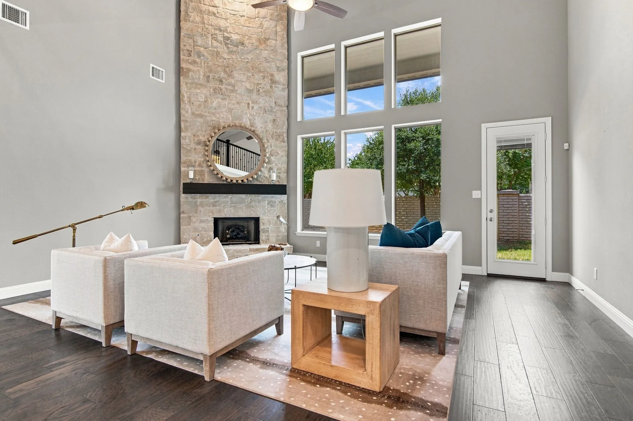 Soaring ceilings featuring a stone-clad fireplace and expansive windows