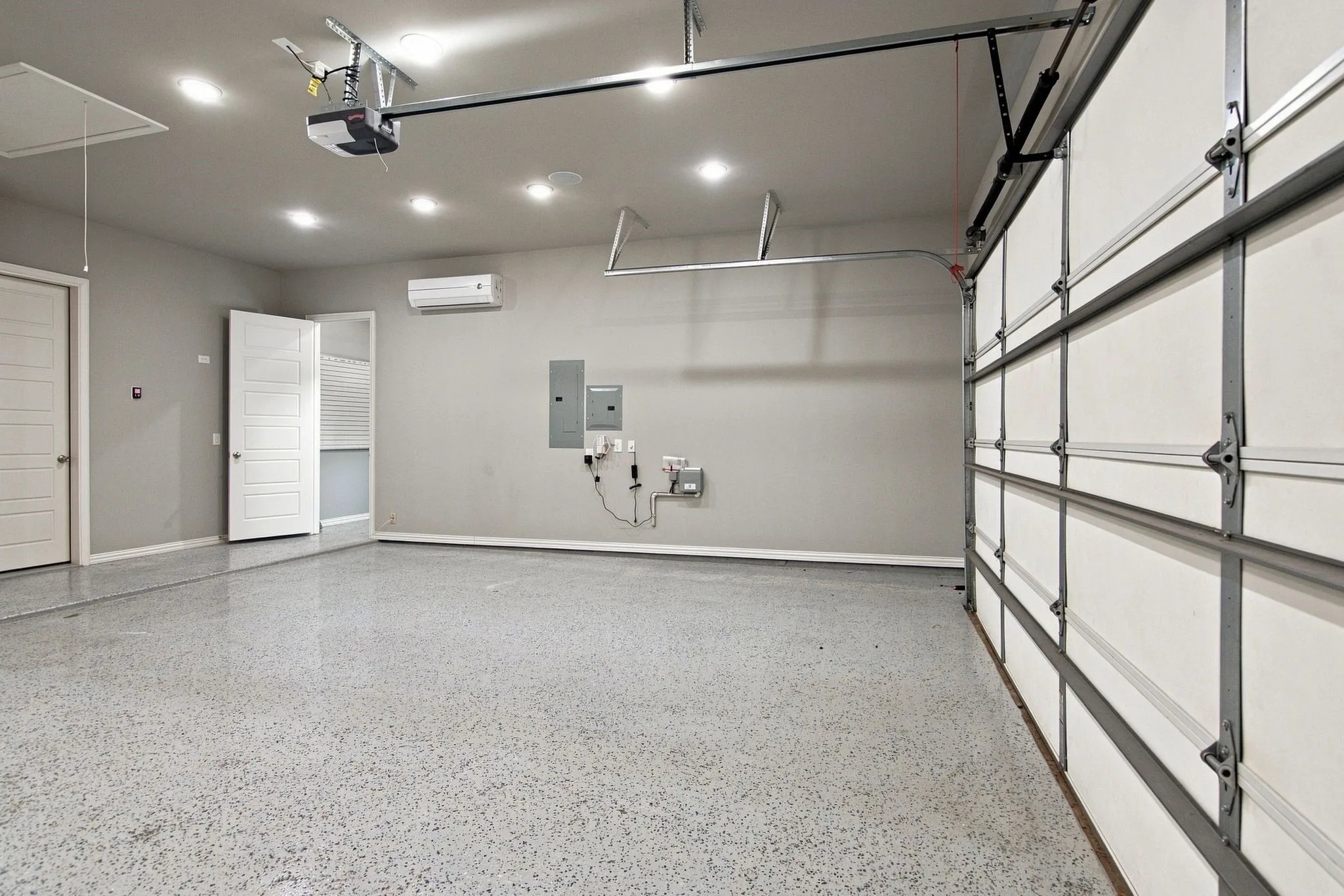 Spacious garage featuring a durable epoxy floor, recessed lighting, and a mini-split air conditioning unit