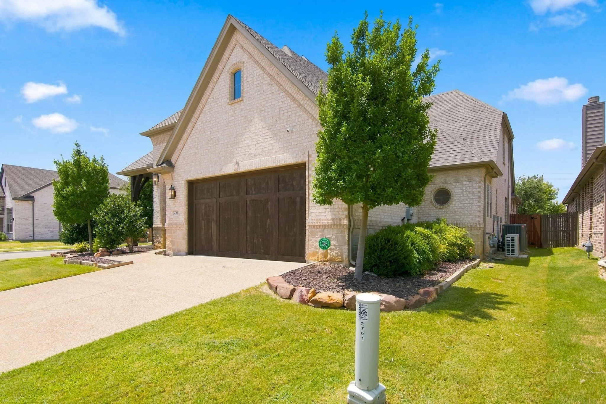 Light brick exterior with a prominent gable roofline, featuring a dark wood-finish garage door