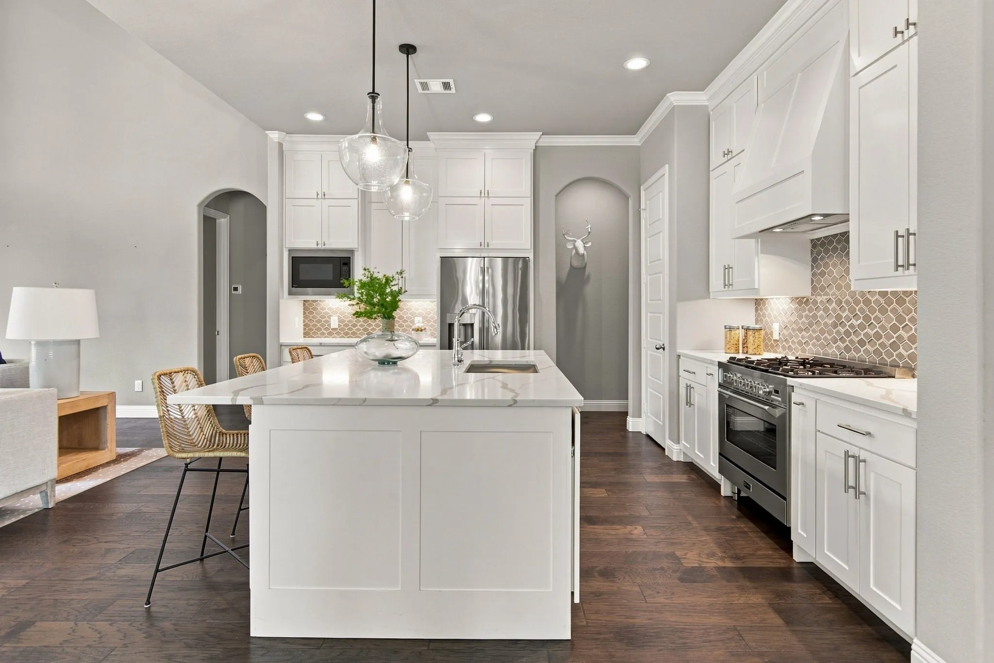 Kitchen featuring white shaker cabinetry, stainless steel appliances, a large center island with a stone countertop, and wood-finish flooring