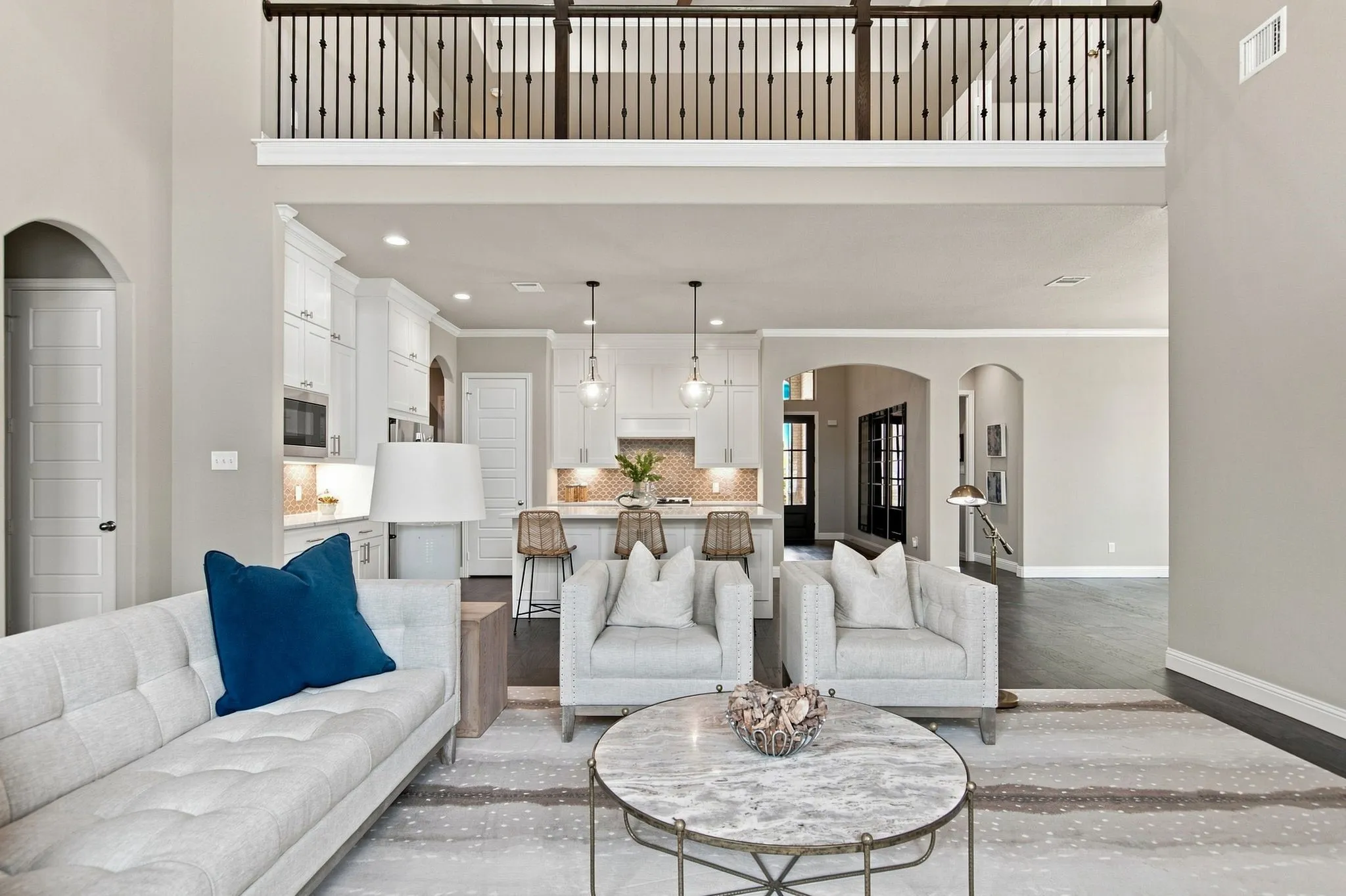 Open-concept living space with a second-story overlook featuring wrought iron balusters