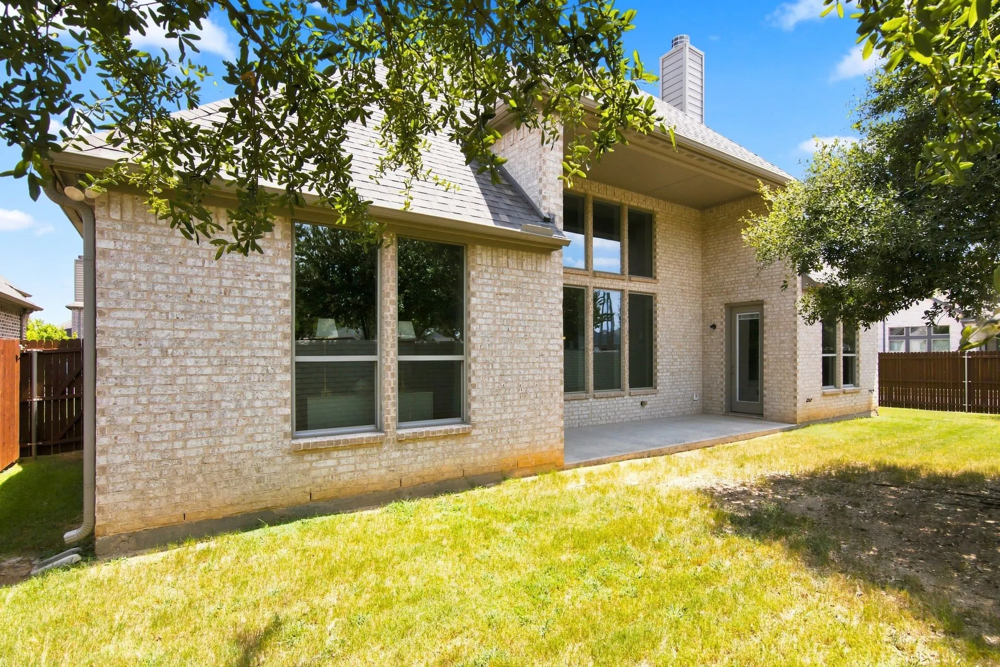 Brick exterior featuring multiple windows and a covered patio