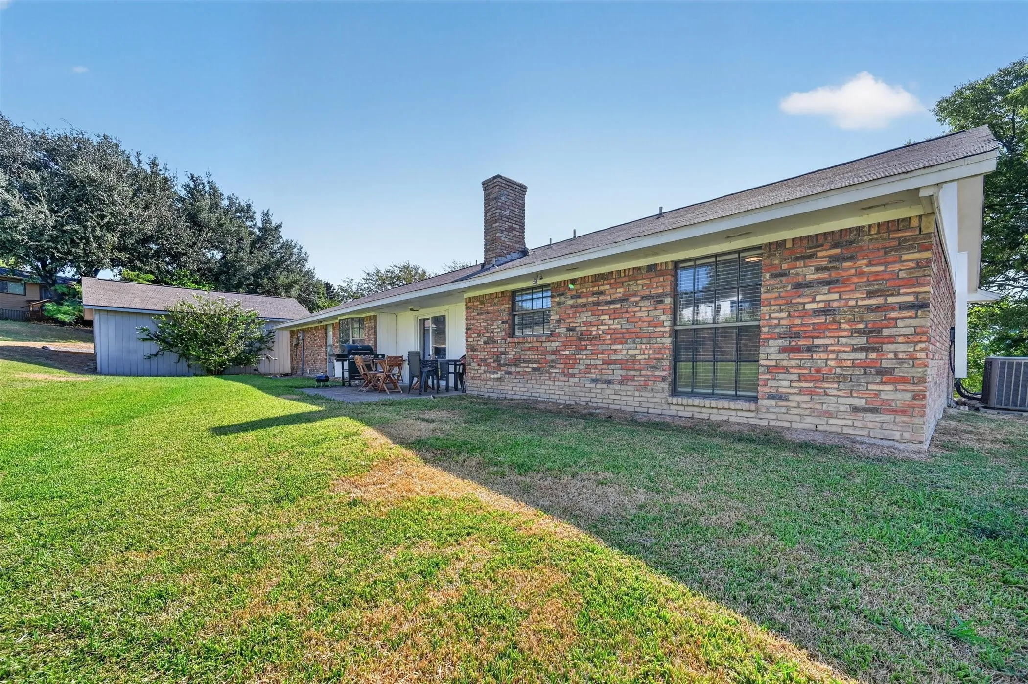 Brick exterior, rear patio, multiple windows, chimney, detached shed structure