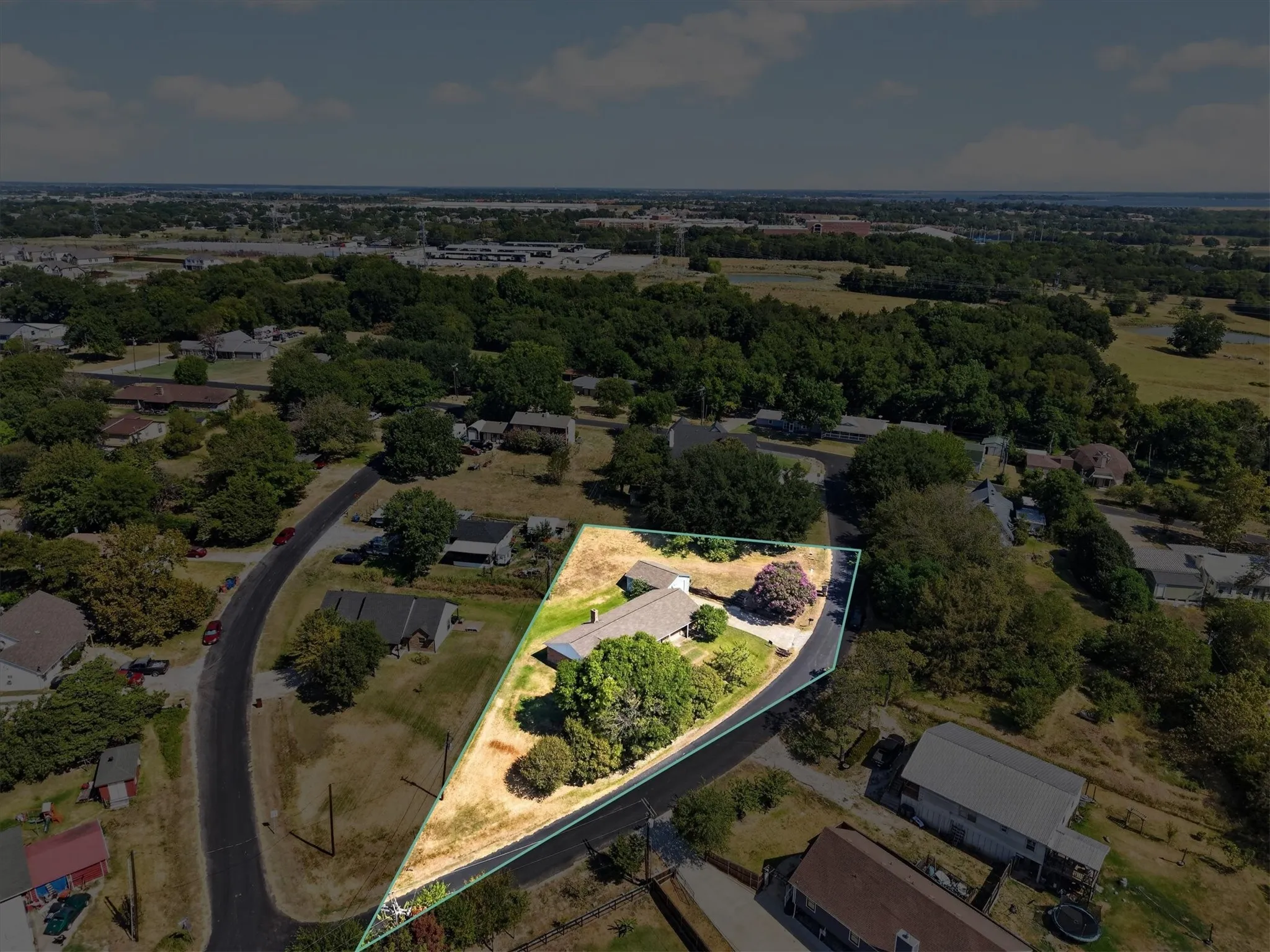 Residential property with a light-colored roof and mature trees, optional additional lot highlighted on north side of photo