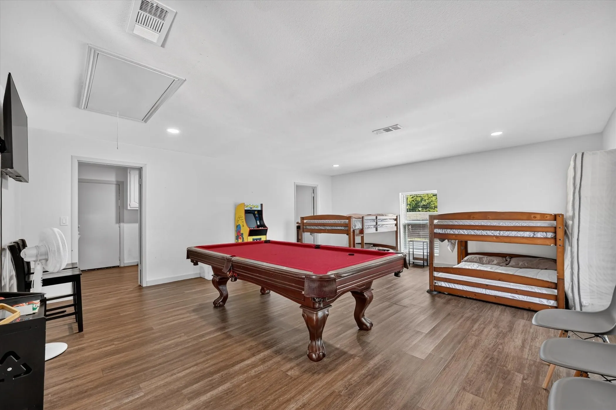 Spacious room featuring wood-finish flooring, recessed lighting, and white wall finishes