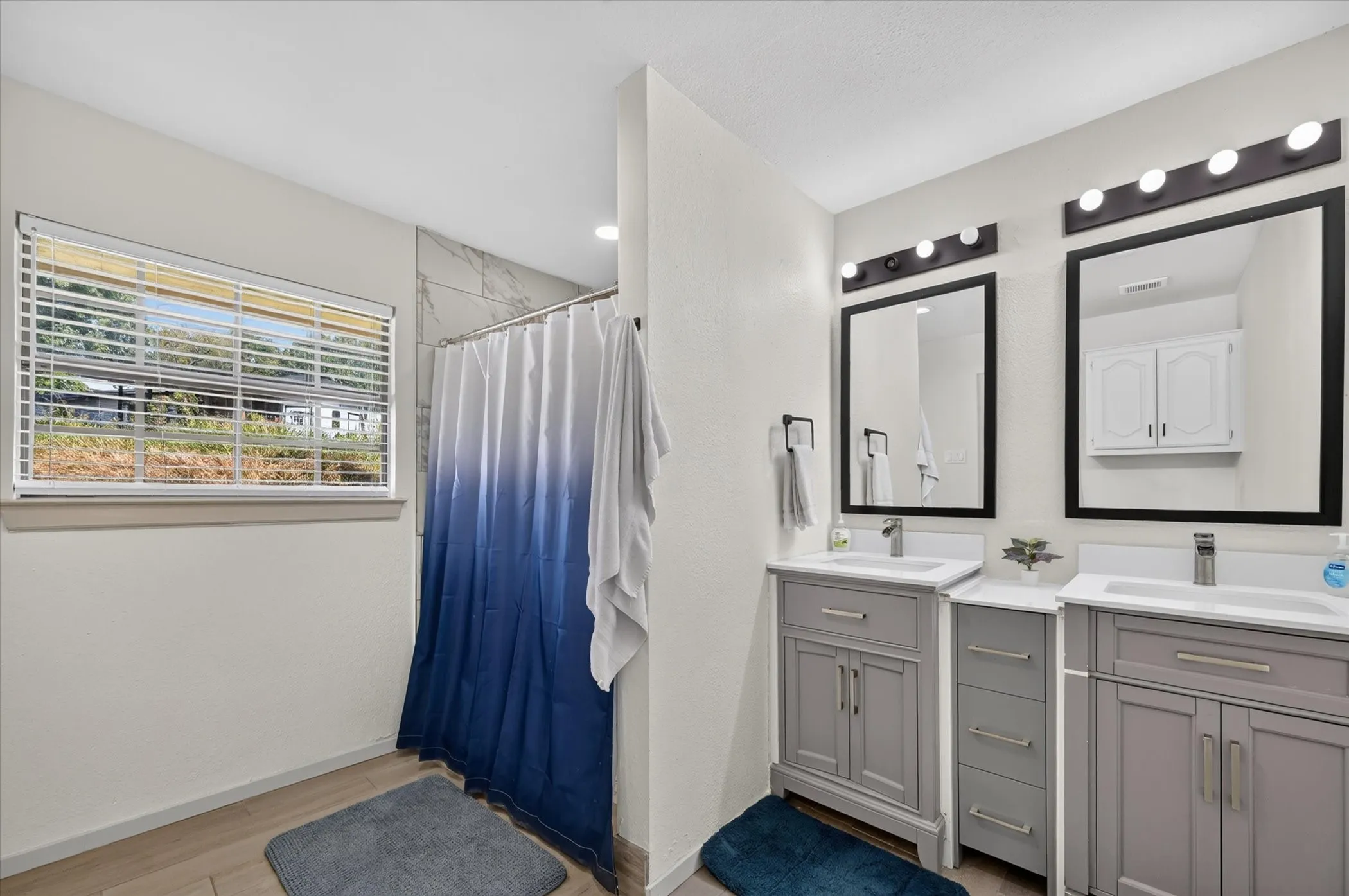 Dual vanity with undermount sinks, gray shaker-style cabinetry, and individual framed mirrors with integrated lighting