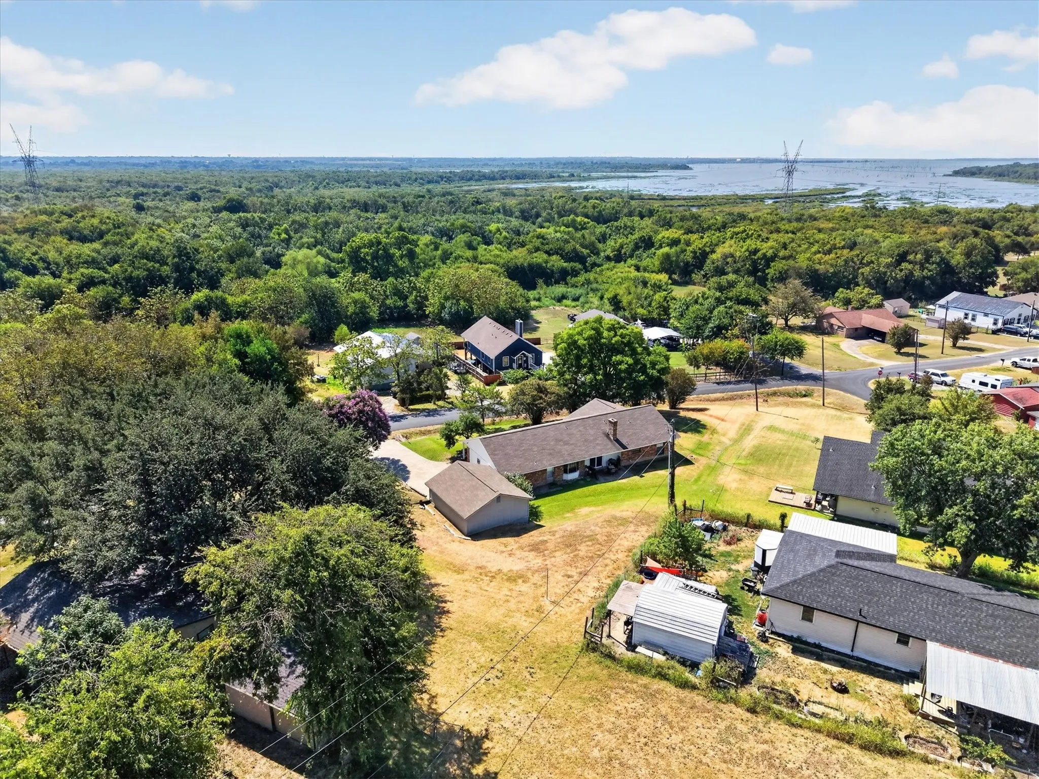 Expansive wooded area, substantial body of water, scattered residential structures, and established trees