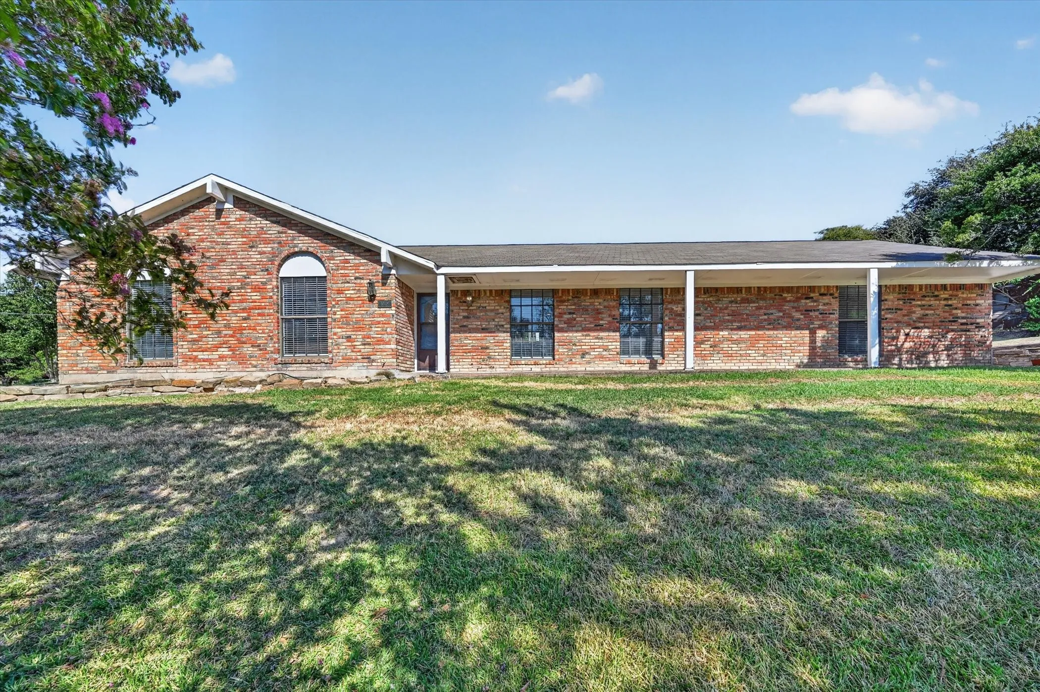 Brick exterior, covered front porch, arched window, and landscaped front yard