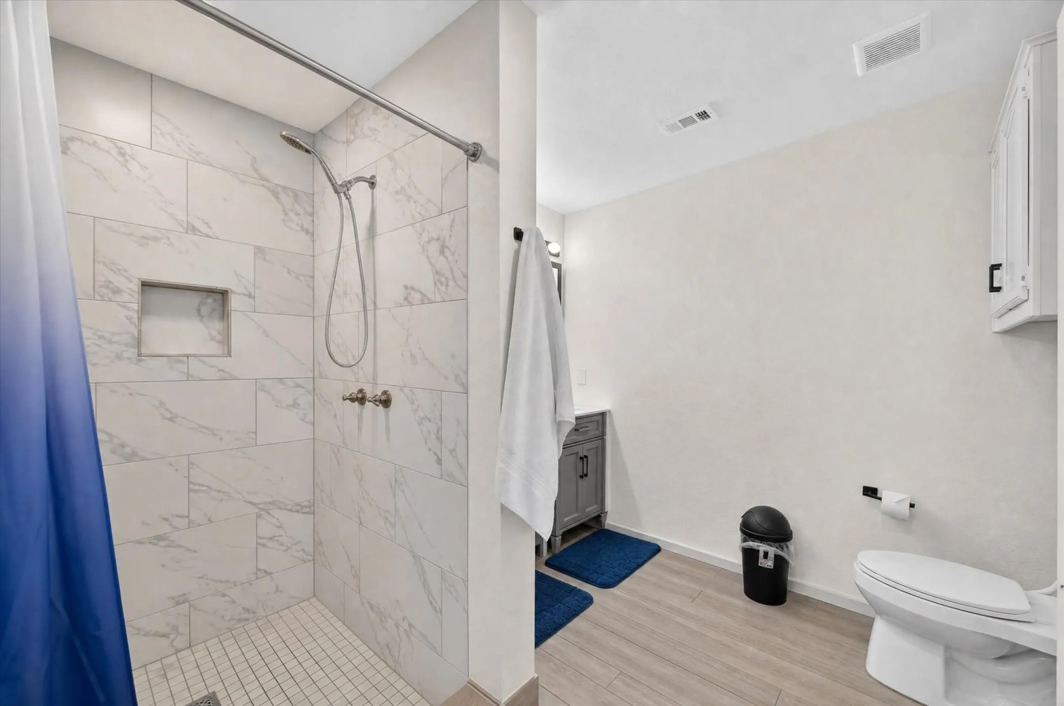 Tiled shower with a built-in niche, featuring a handheld showerhead and wall-mounted controls