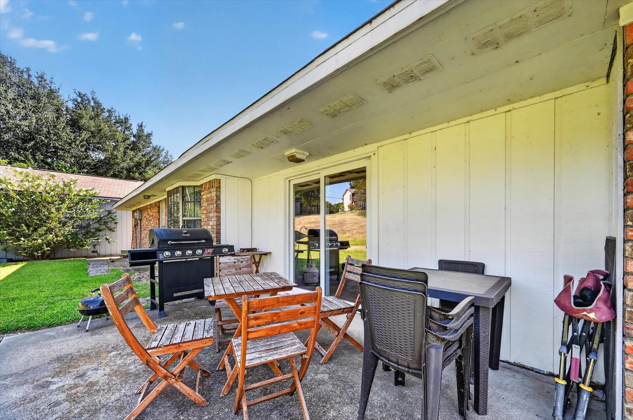 Concrete patio with a covered overhang, sliding glass door entry, and brick exterior accents