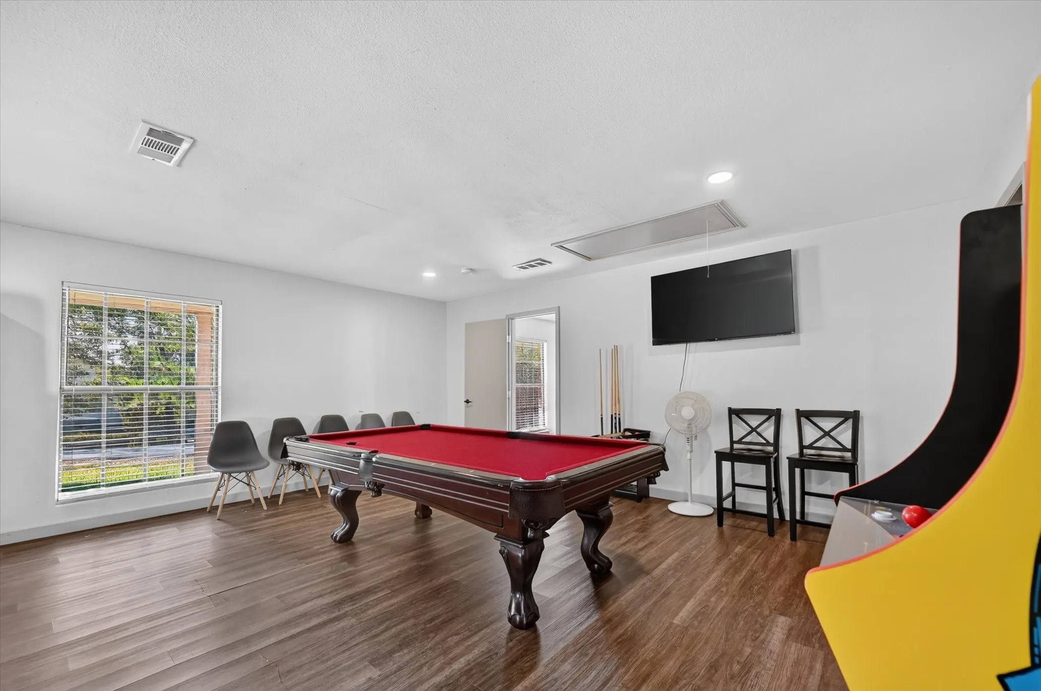 Spacious room featuring wood-finish flooring and a large window with blinds