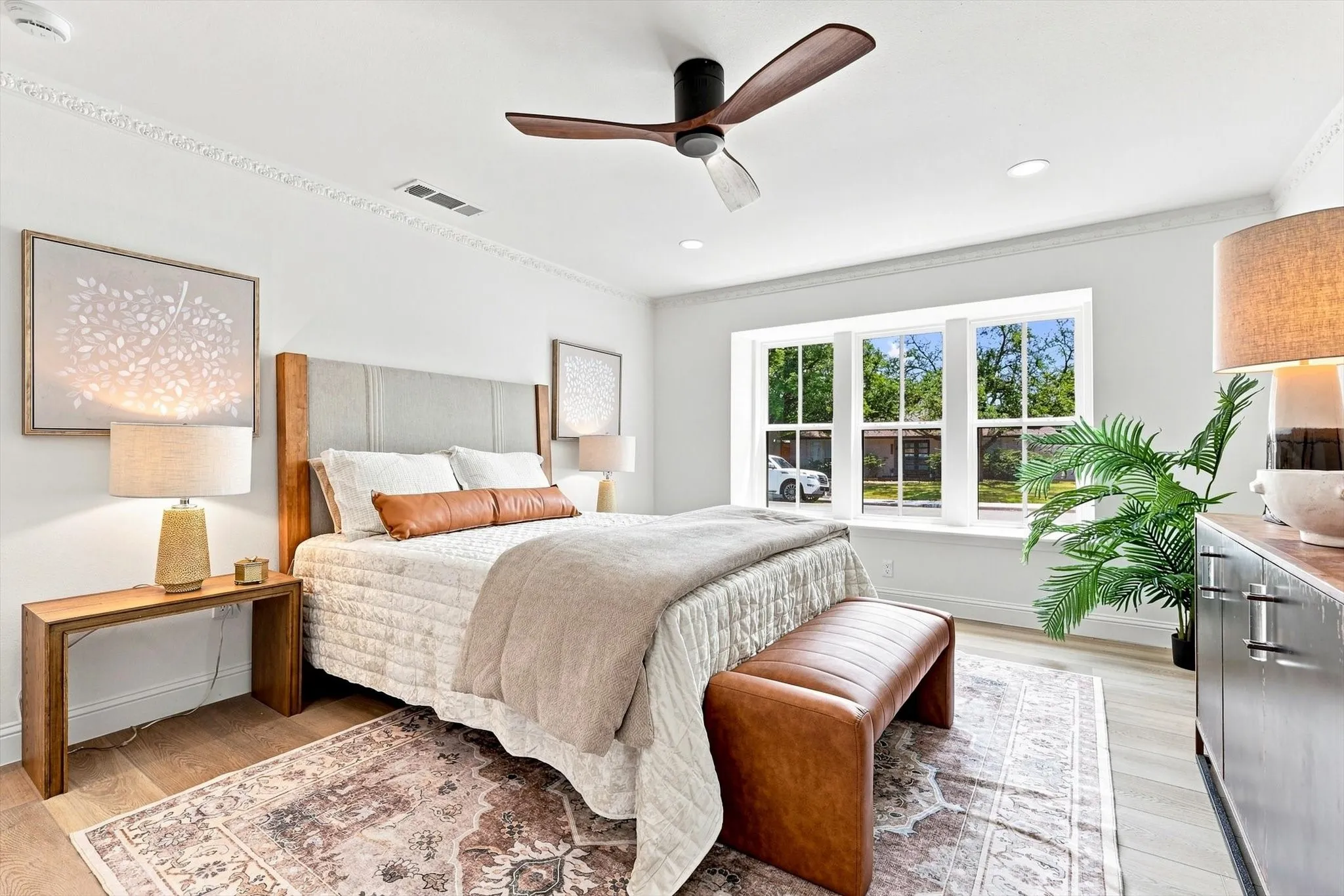 Primary bedroom with new flooring, new windows, ceiling fan and lots of natural lighting