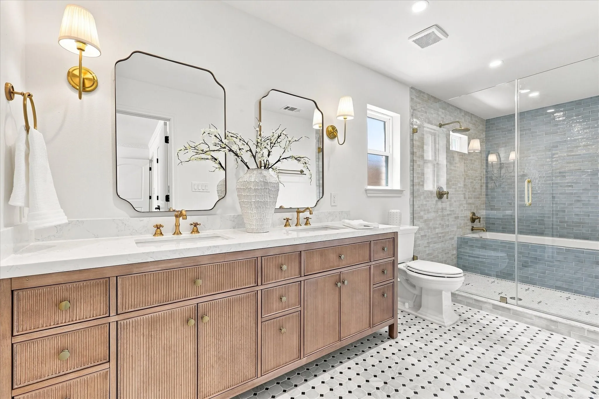 Incredible luxurious primary bathroom with custom tiled separate shower and oversize tub. Custom cabinets with quartz countertops with updated flooring, fixtures and mirrors.