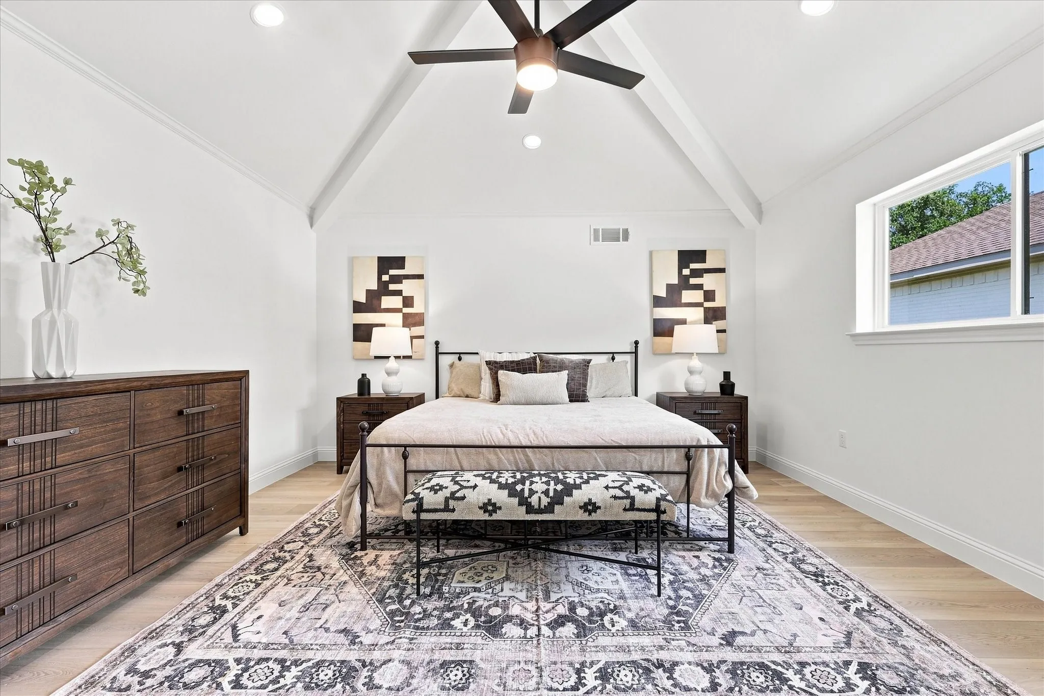 Bedroom 3 being staged as a secondary primary suite with vaulted ceiling, wood beams, new windows and ceiling fan.