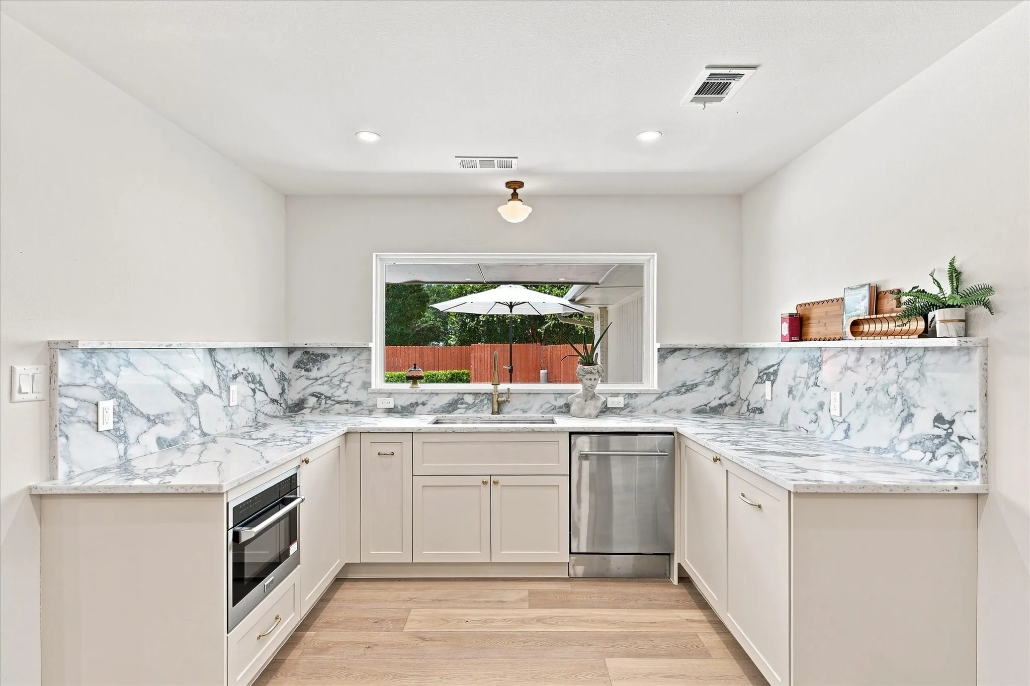 Beautiful view of pool from oversize kitchen window. This space features farm sink, Zline dishwasher and microvave, pull-out trash bin, quartz countertops with accent shelving