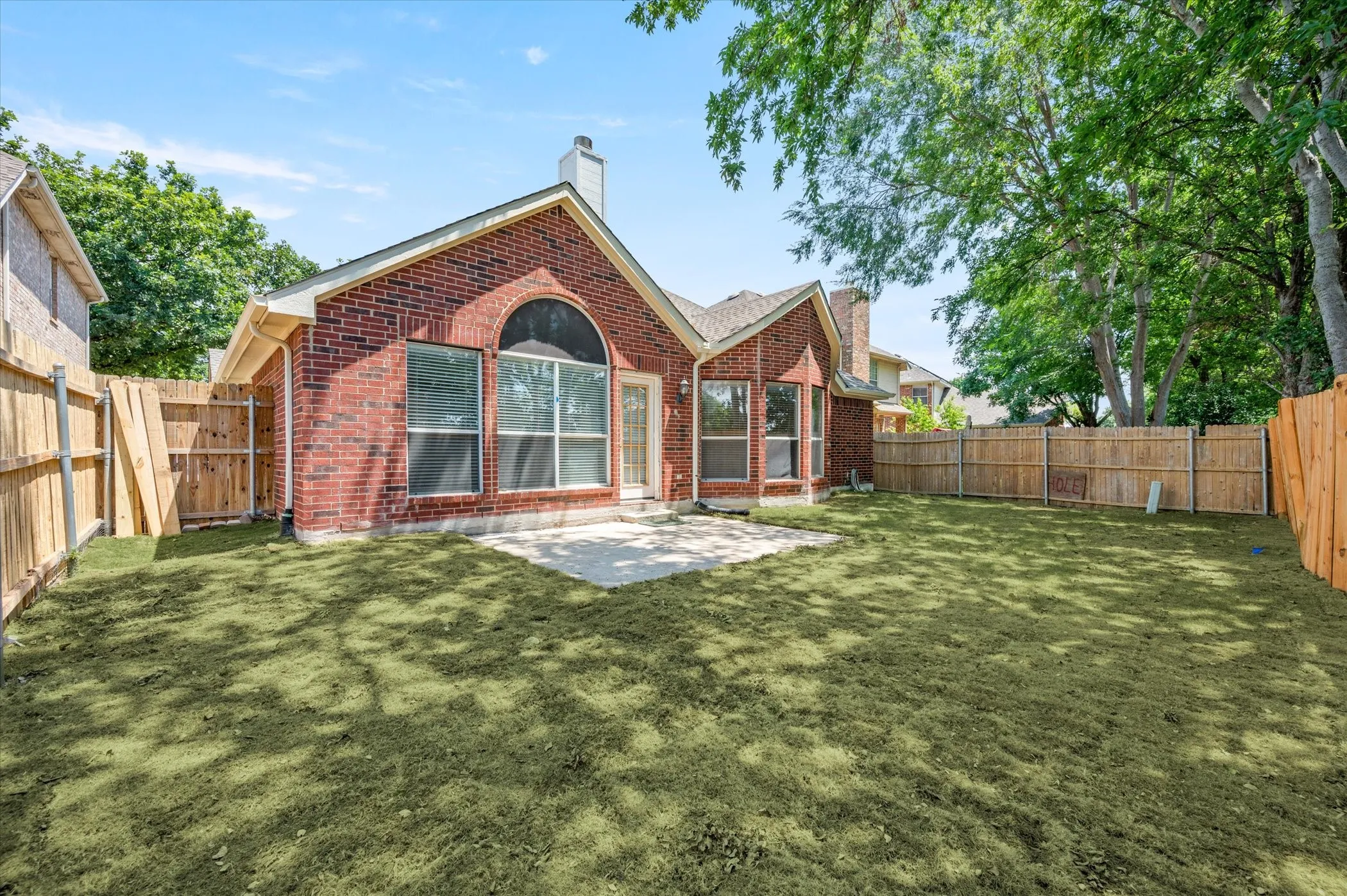 Brick exterior with multiple windows, a rear patio, and a fenced backyard