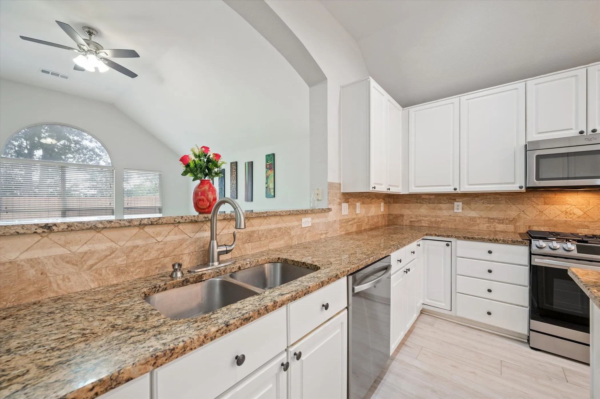 Kitchen featuring white cabinetry, granite countertops, stainless steel appliances, a tile backsplash, and wood-finish flooring