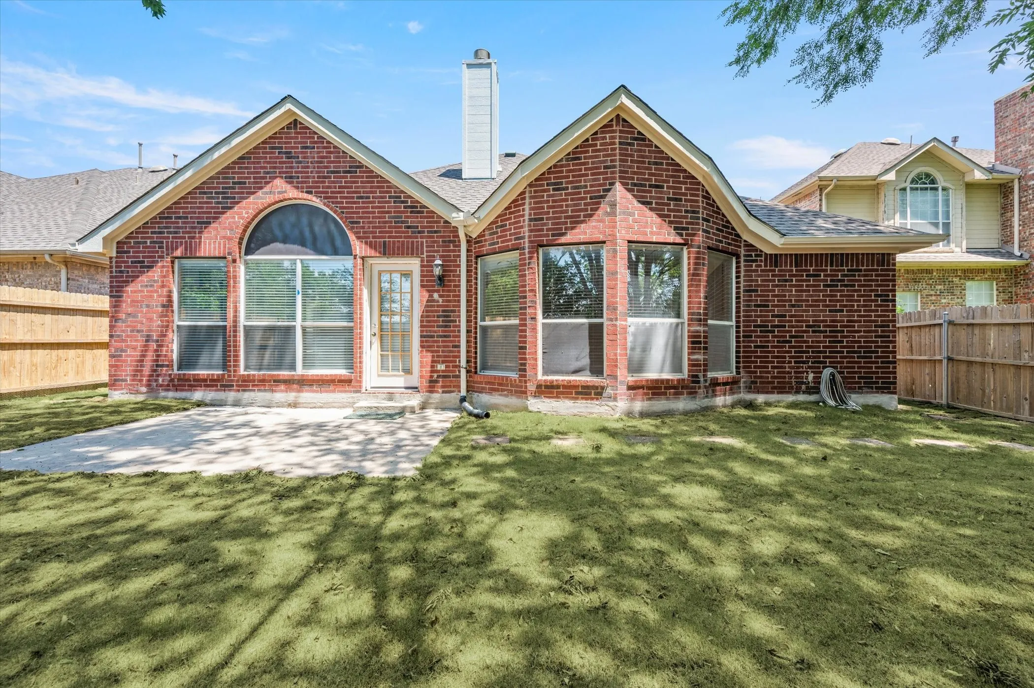Brick exterior with an arched window, multiple large windows, and a glass-paneled door