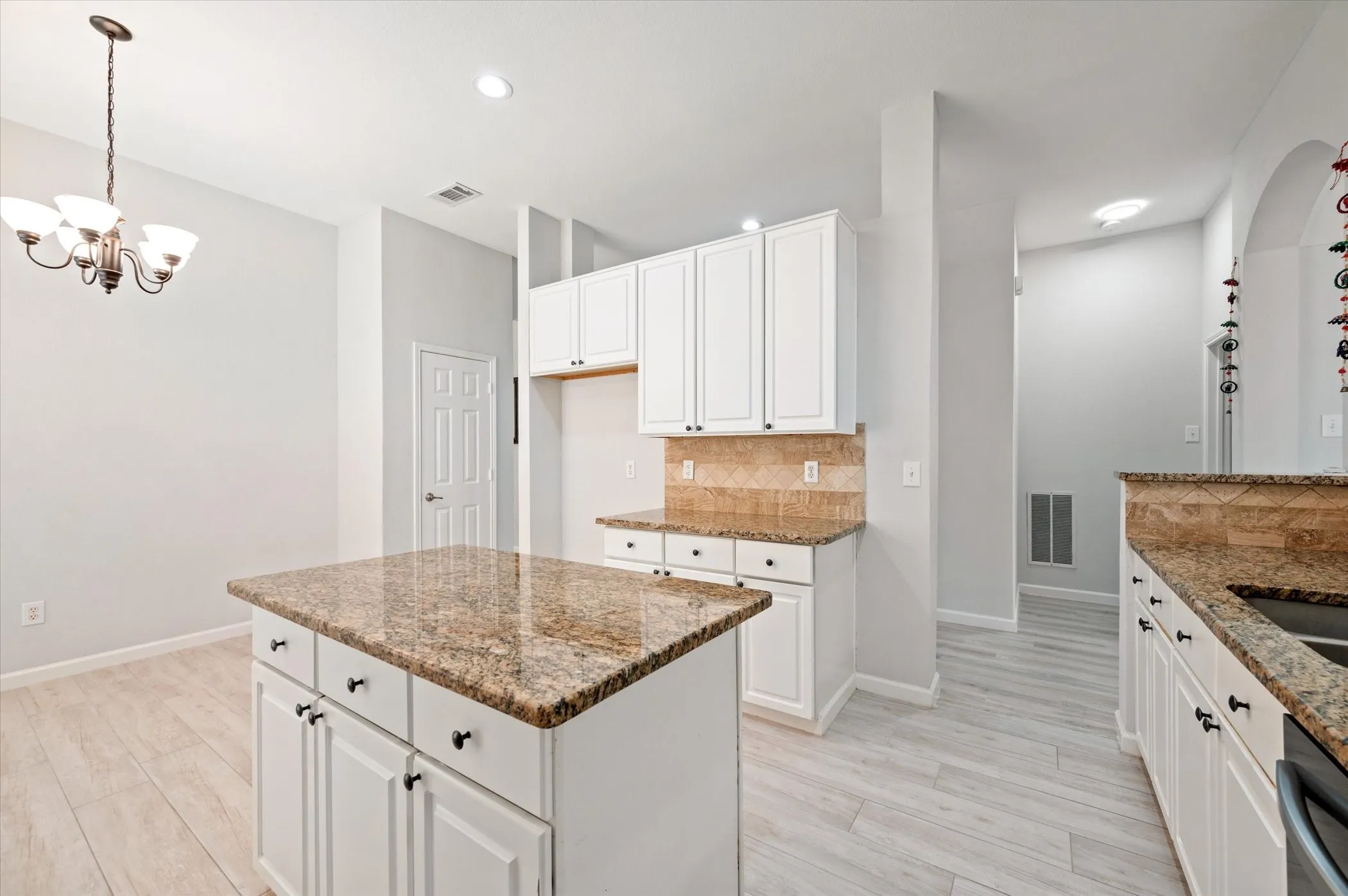 Kitchen featuring a center island with a stone countertop, white cabinetry with dark hardware, recessed lighting, and wood-finish flooring