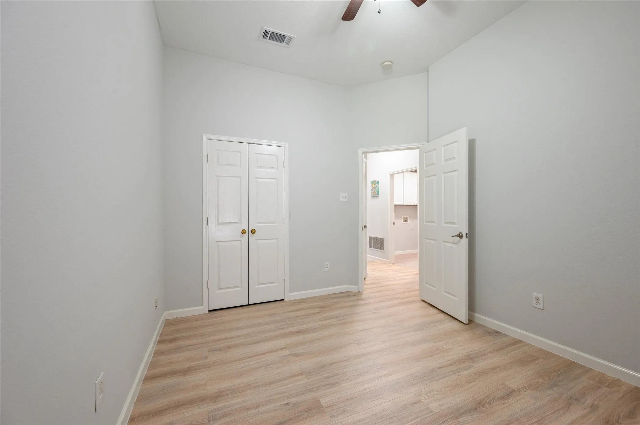 Vaulted ceiling with a ceiling fan, wood-finish flooring, and a bifold closet door