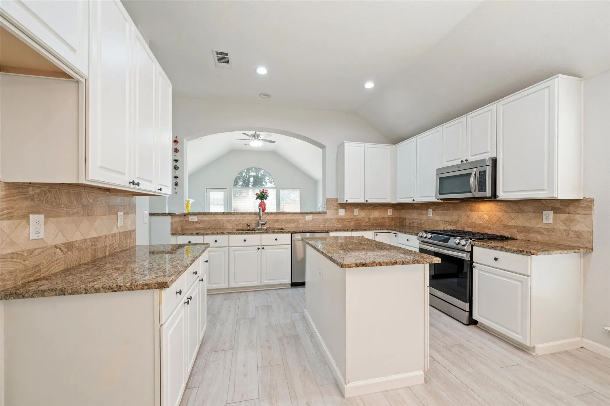 Kitchen featuring a central island, recessed lighting, stainless steel appliances, wood-finish flooring, and white cabinetry with dark hardware