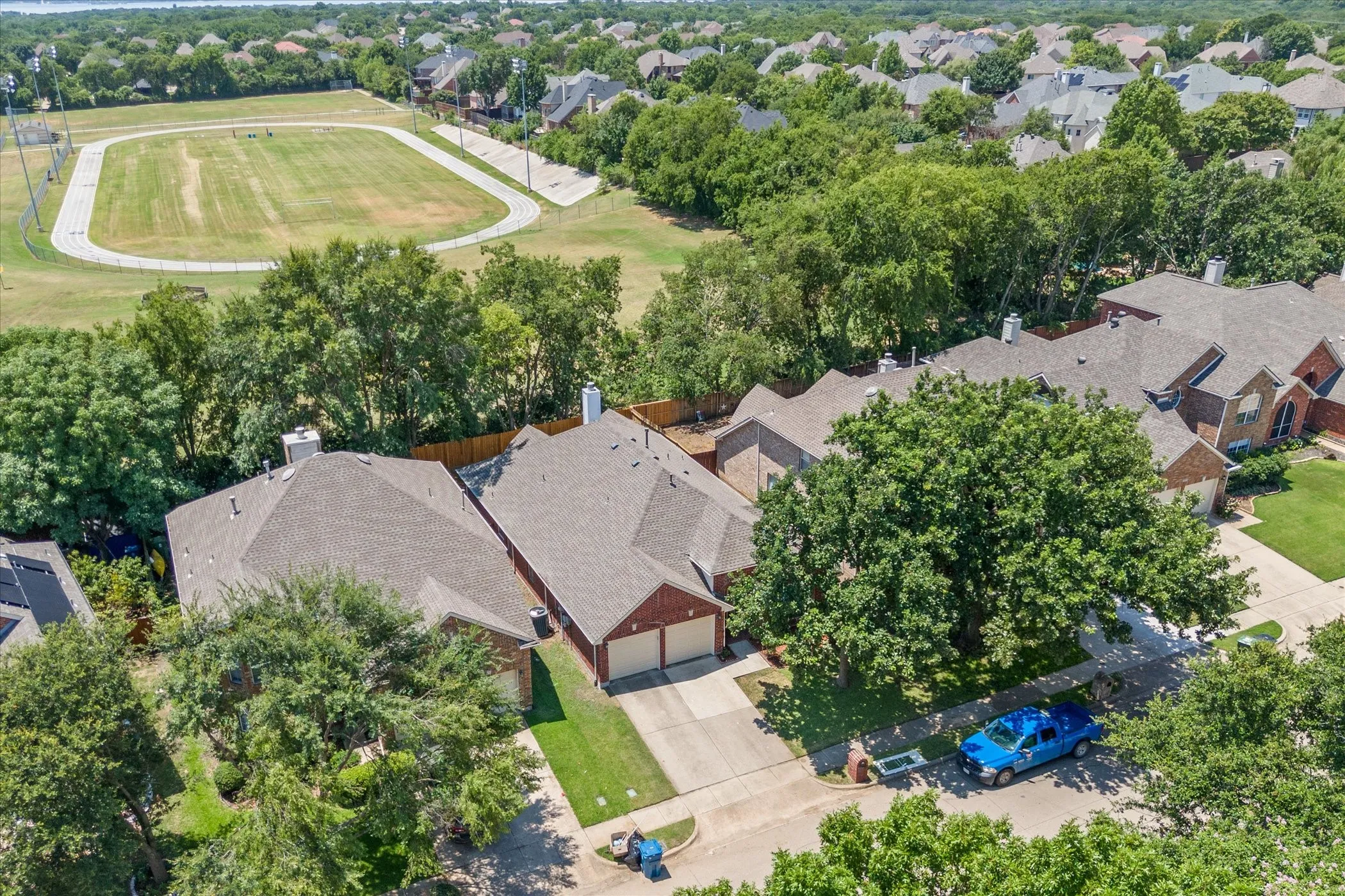 Brick exterior residence with a two-car garage, mature front yard trees, and a paved driveway