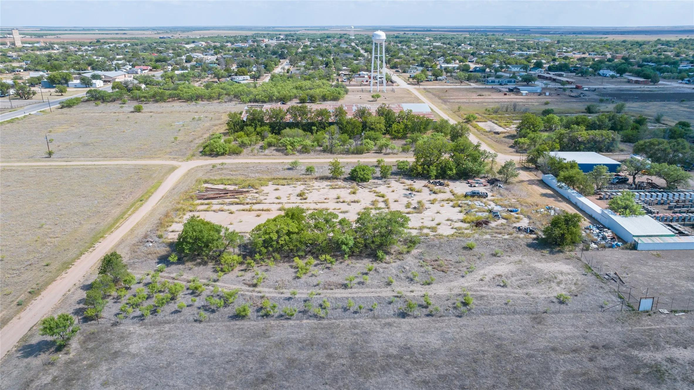 Expansive land parcel with surrounding foliage and an adjacent commercial building