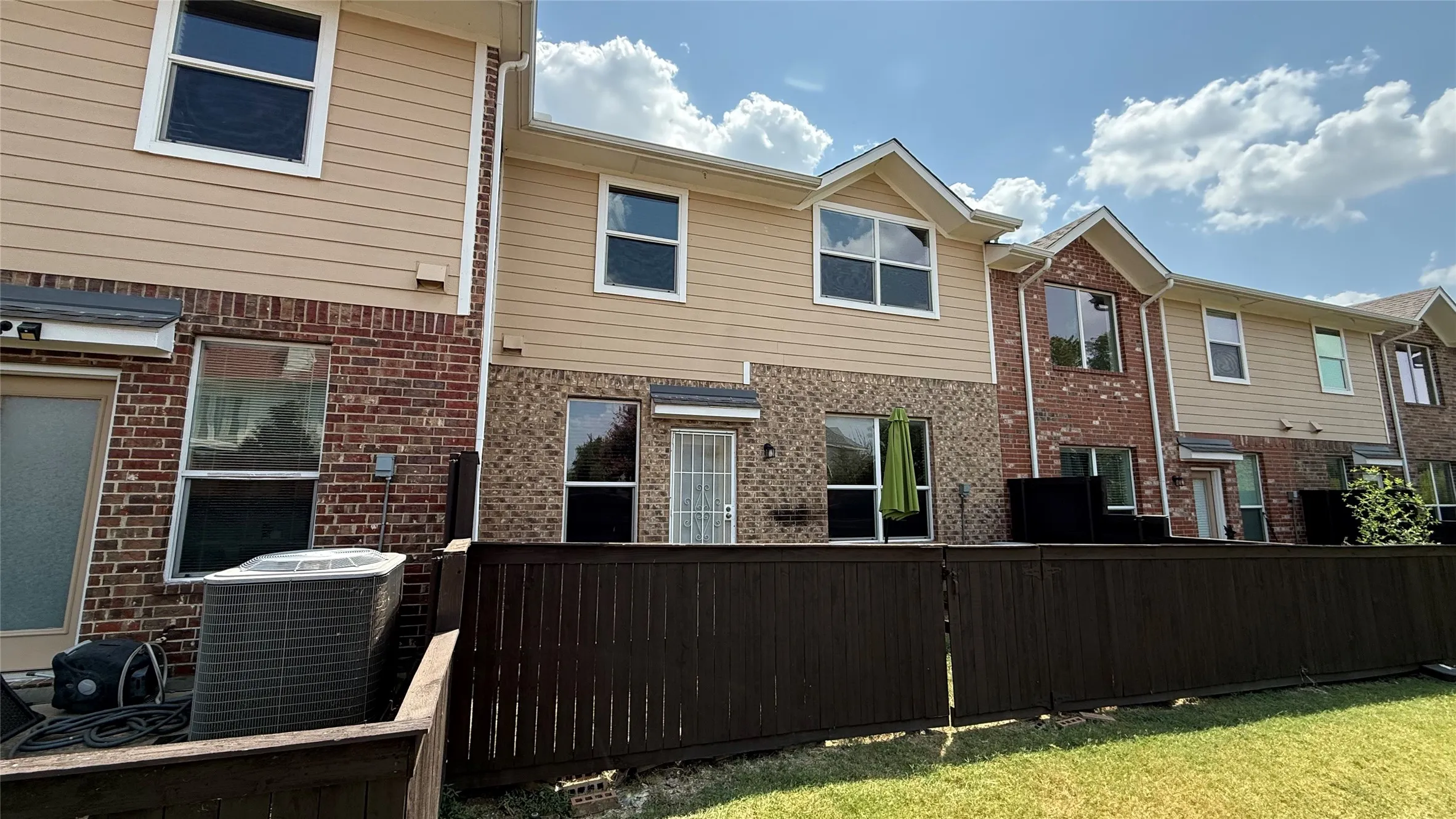 Multi-level residence featuring brick and siding exterior, multiple windows, and a private fenced yard space