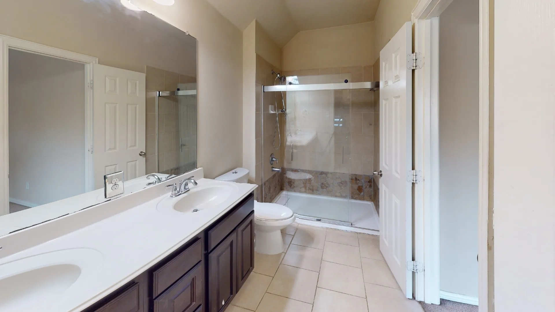 Double vanity with integrated sinks, full-width mirror, and dark wood-finish cabinetry