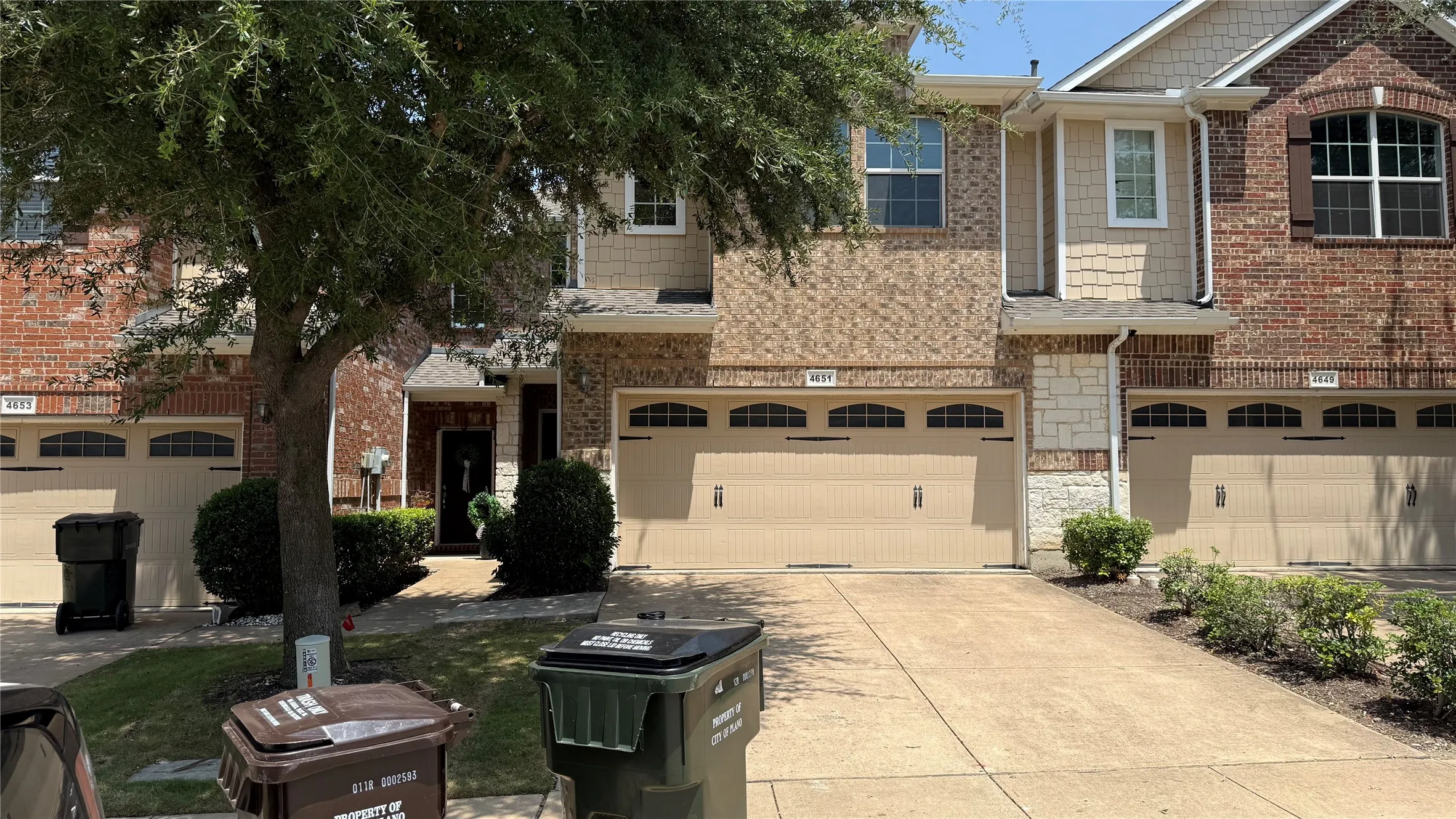 Brick and stone exterior with arched garage doors, decorative window shutters, and a concrete driveway