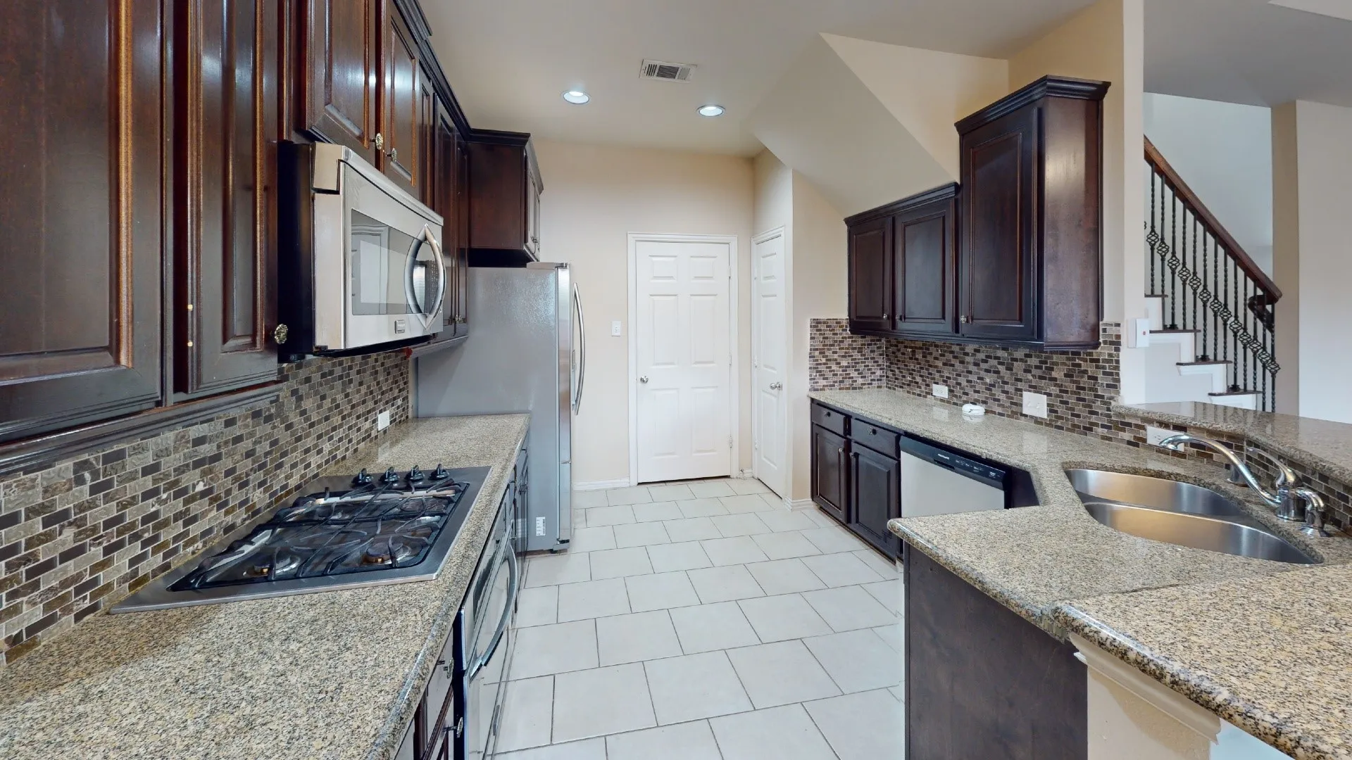 Kitchen featuring dark wood cabinetry, granite countertops, mosaic tile backsplash, stainless steel appliances, and tile flooring
