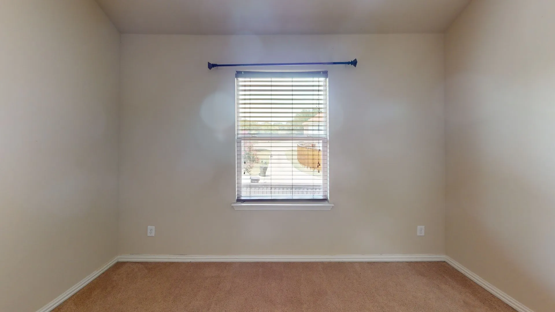 Carpeted flooring, single window with blinds, window sill, and a dark finish curtain rod